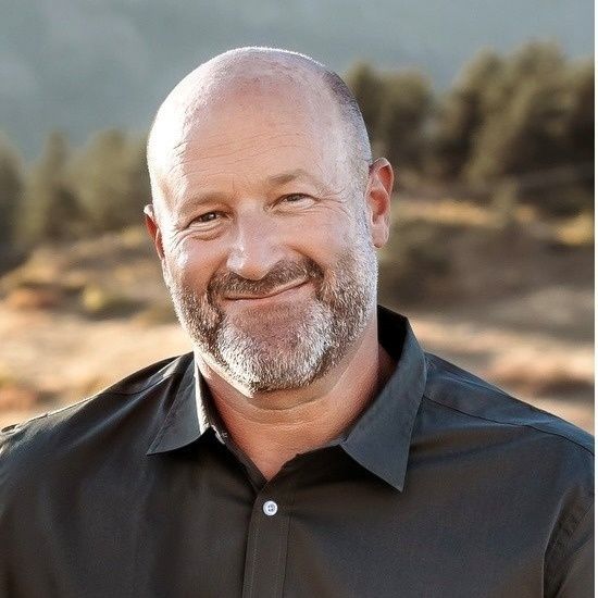 A bald man with a beard wearing a black shirt