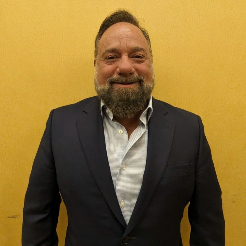A man with a beard is wearing a suit and smiling