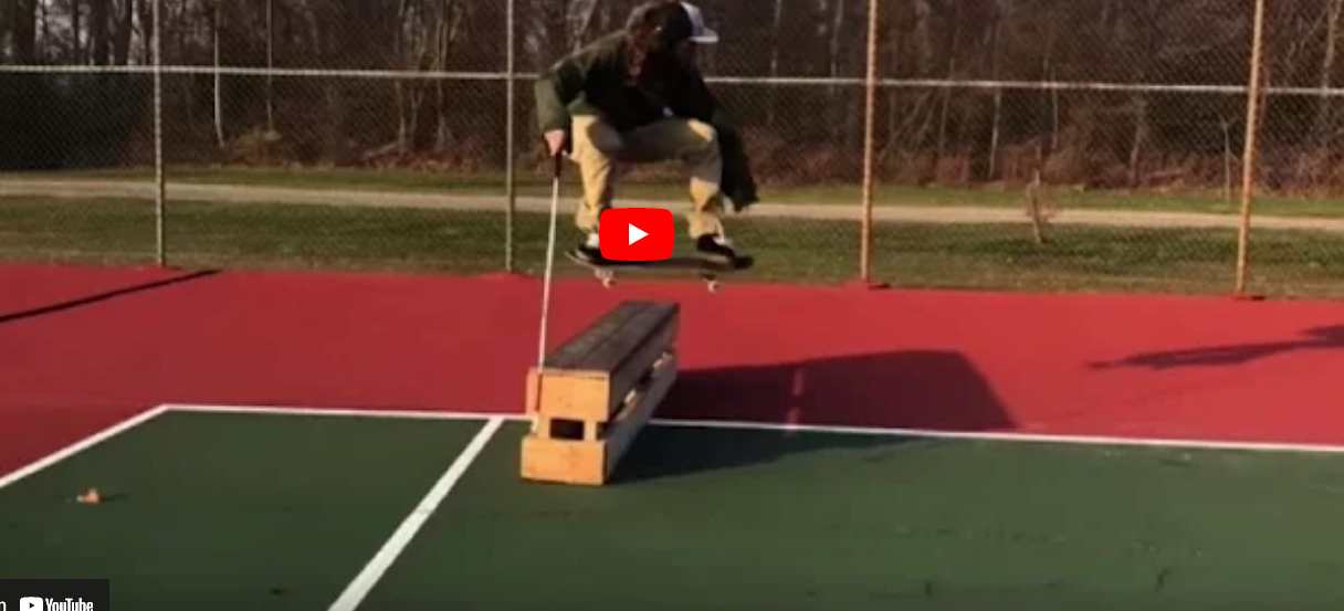 Dan Mancina is mid-air in the middle of a skateboard flip trick.