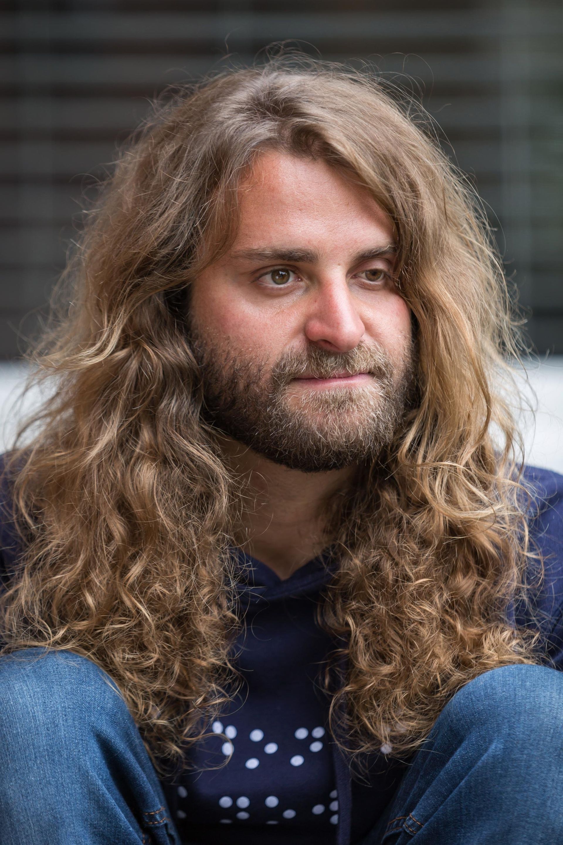 A closeup shot of founder Dan Mancina. He has long, curly, light brown hair and a brown beard.