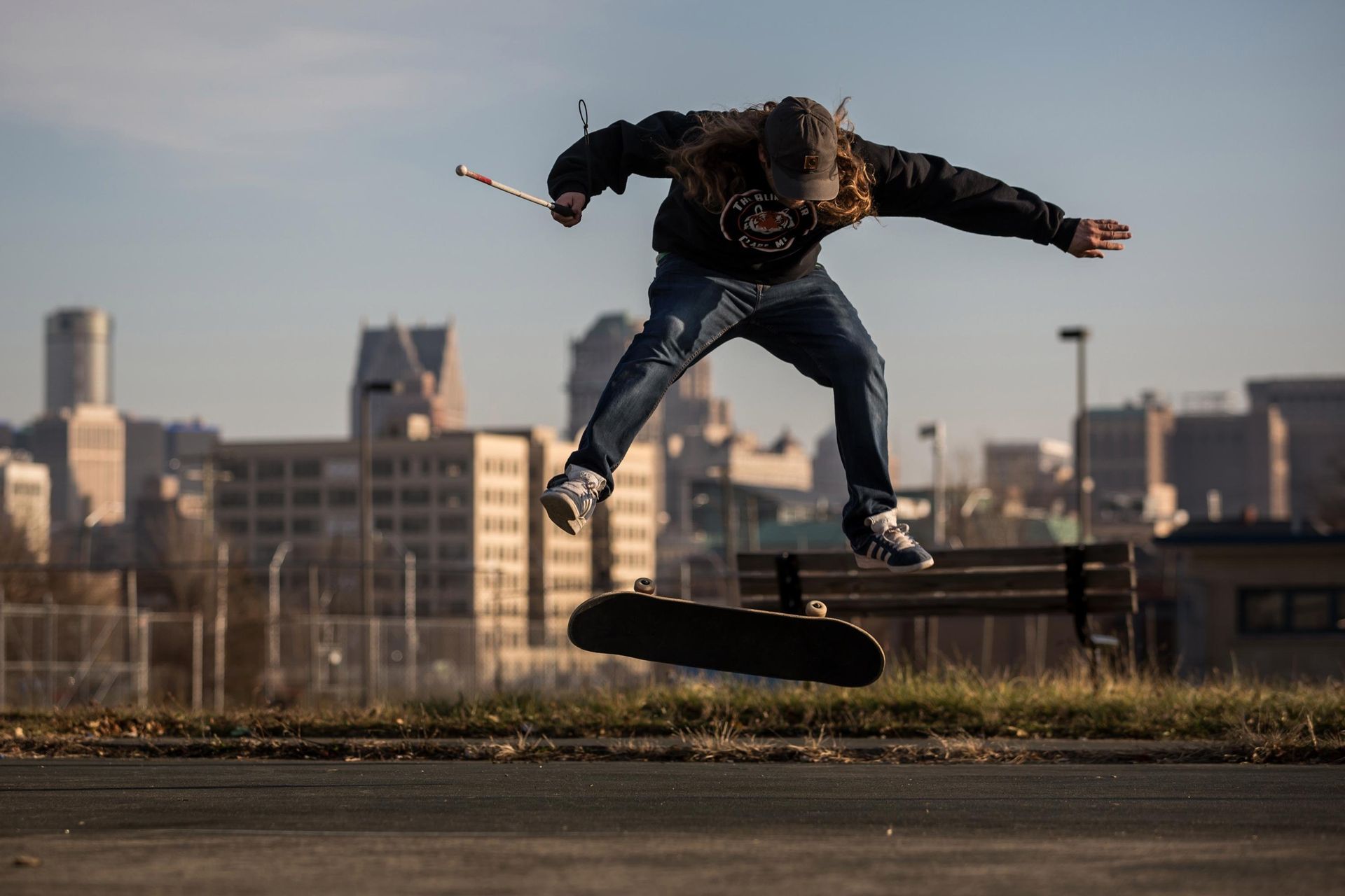 Dan Mancina is midair doing a skateboard flip trick with a cityscape in thebackground.