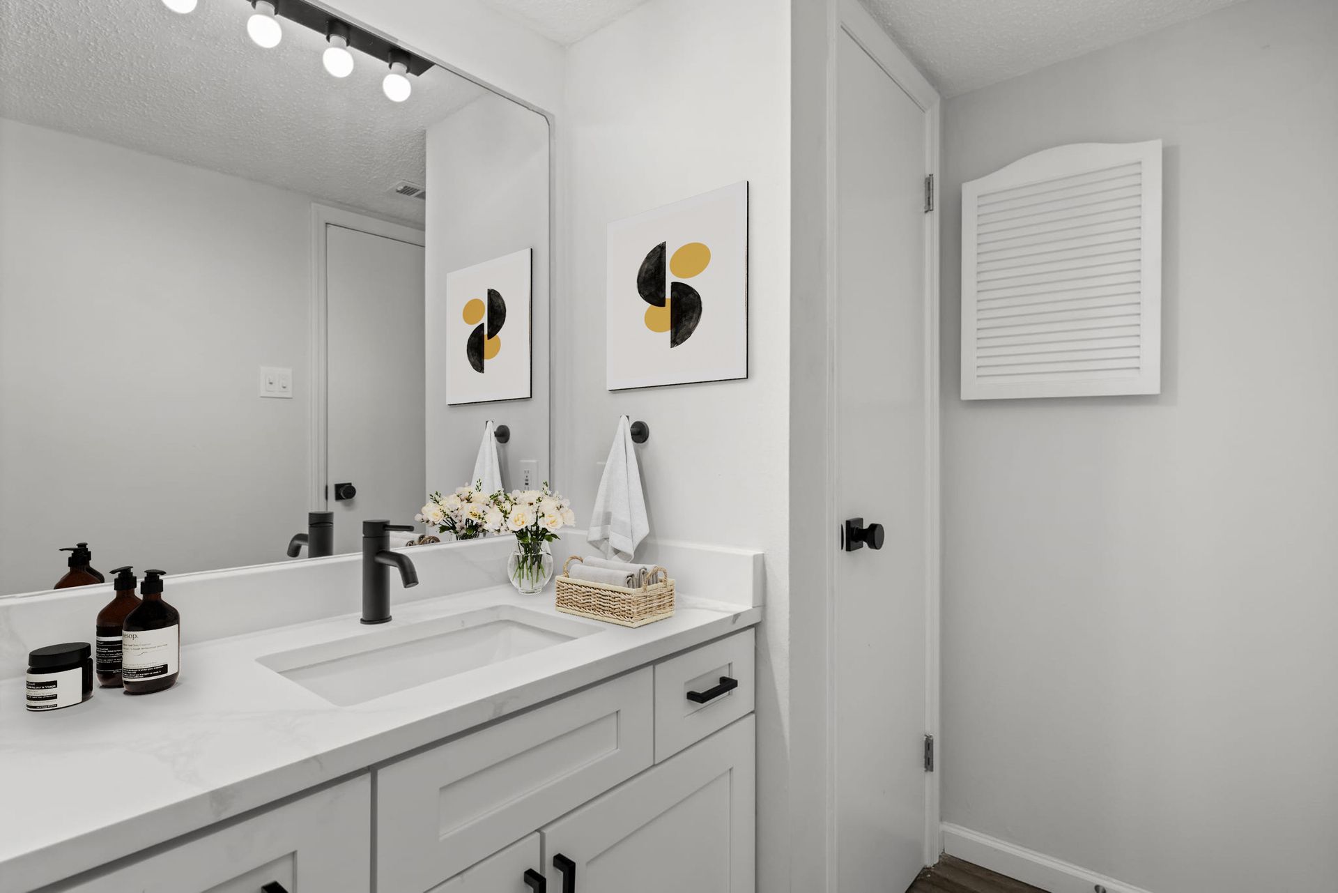 A bathroom with a sink , mirror and cabinets.