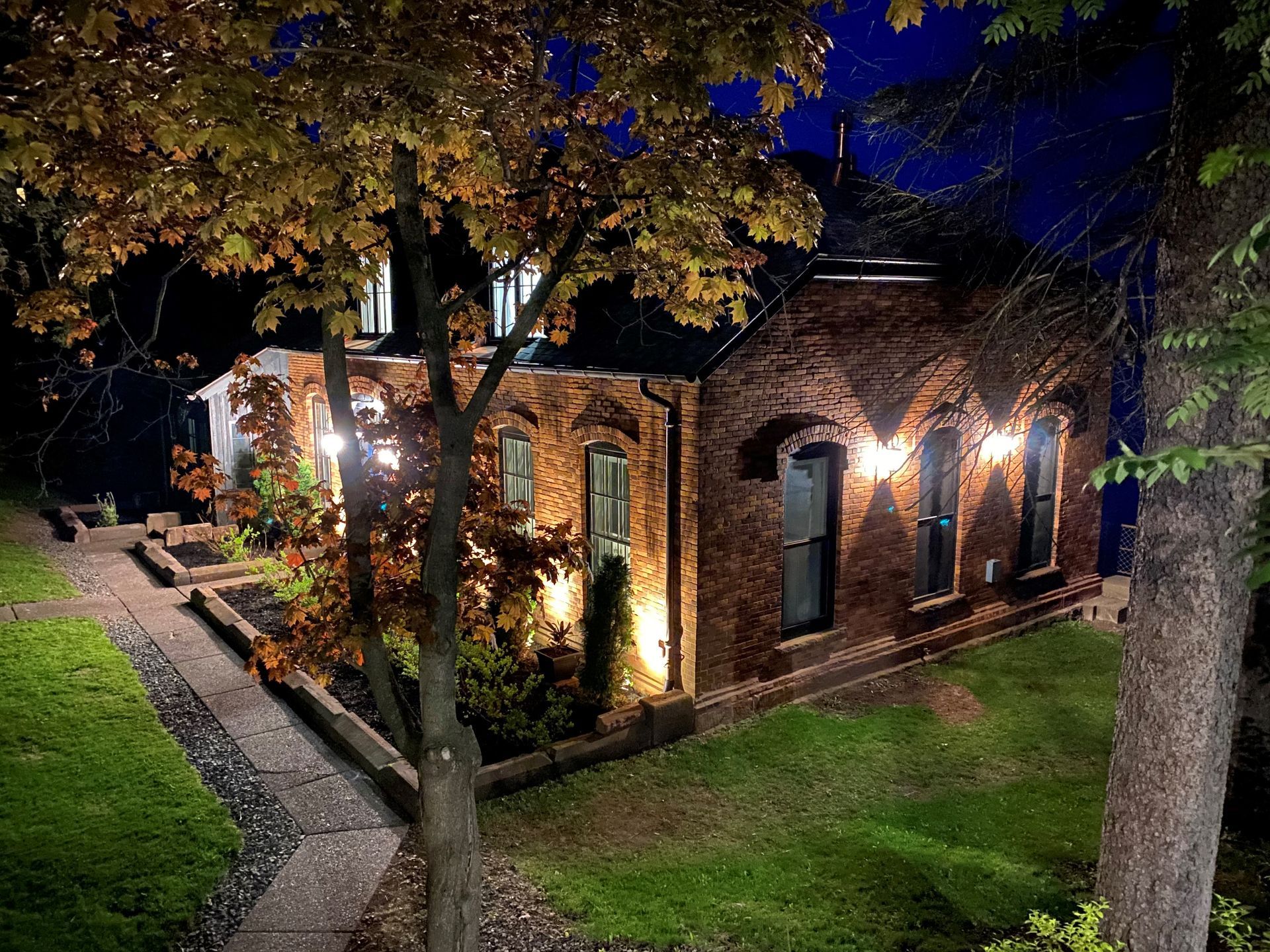 A narrow kitchen pantry with gray cabinets, countertop, and wine fridge. Soft lighting illuminates the space.