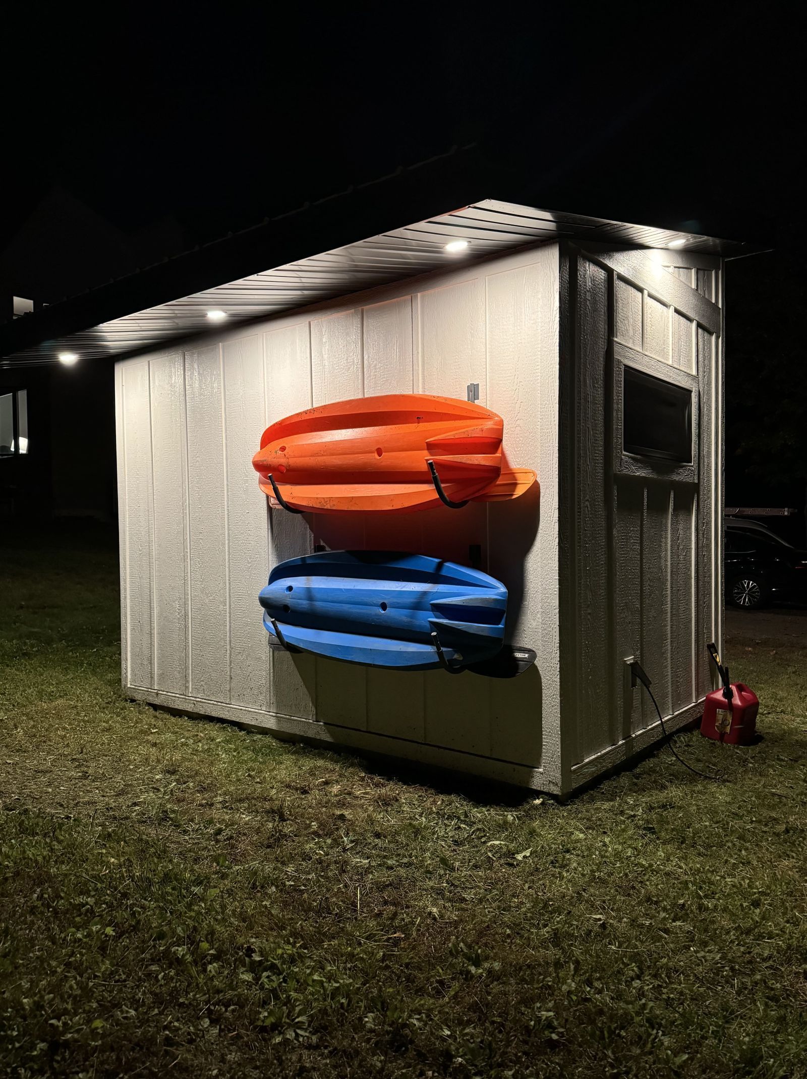 A small shed with inflatable rafts hanging on the side, illuminated at night.