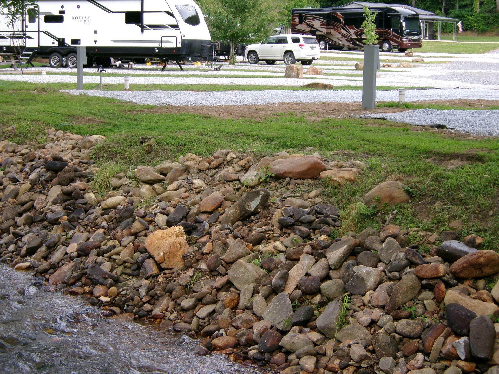 A gravel driveway leading to a picnic table in the woods.