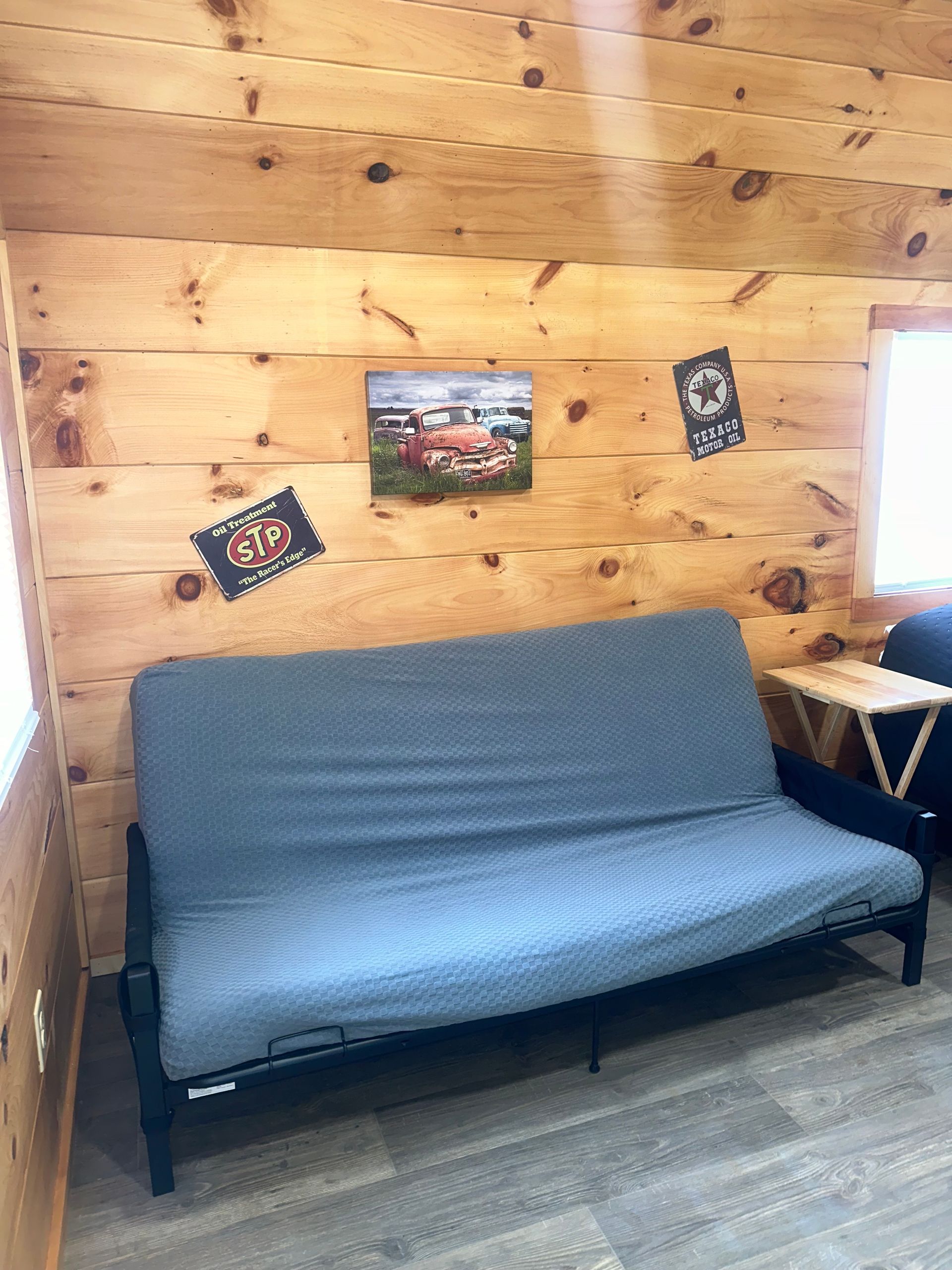 A futon is sitting in a room with a wooden wall.