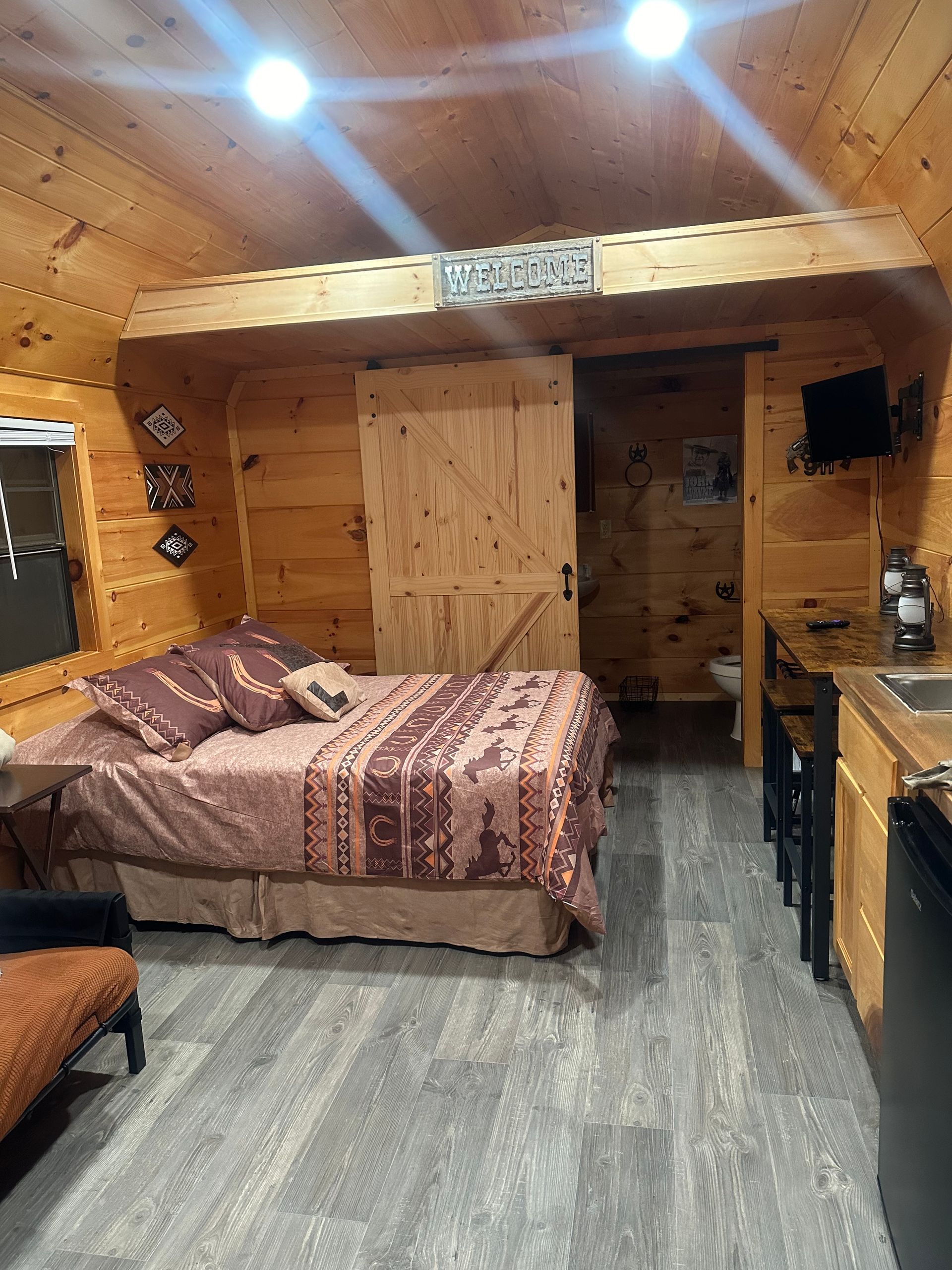 A bedroom in a log cabin with a bed and a kitchen.