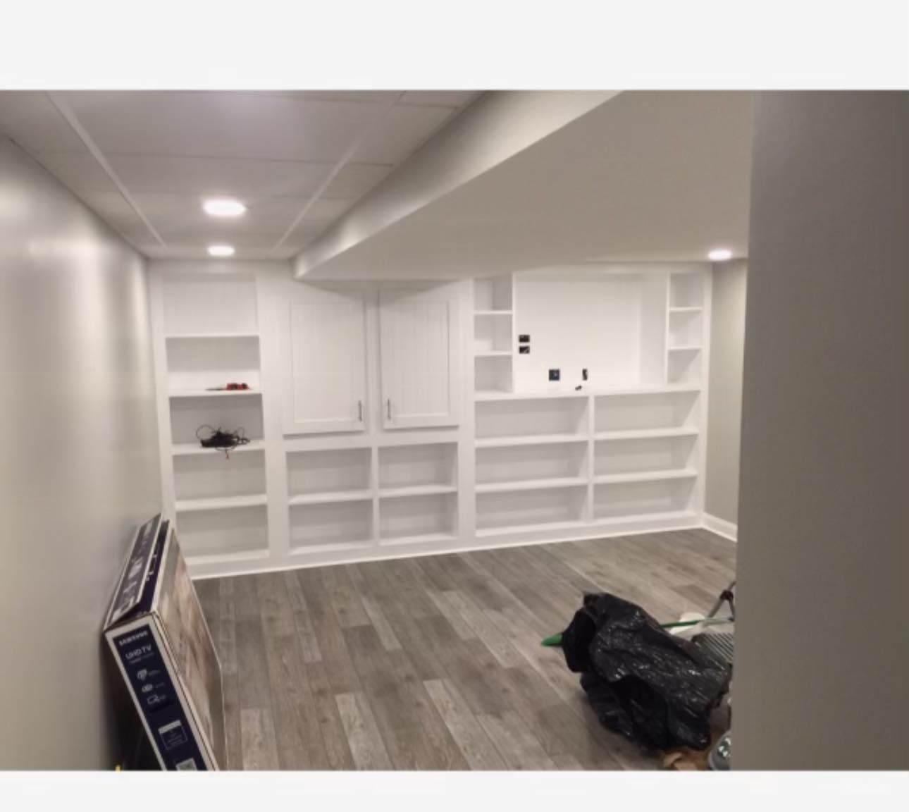 A wooden door is open to a gray wall with potted plants in front of it.