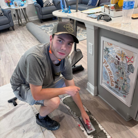 A man is kneeling down in front of a florida map on a wall.