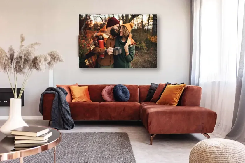 Canvas print on a wall with two people walking on the beach at sunset
