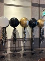 A row of black and gold balloons on stands in a room.