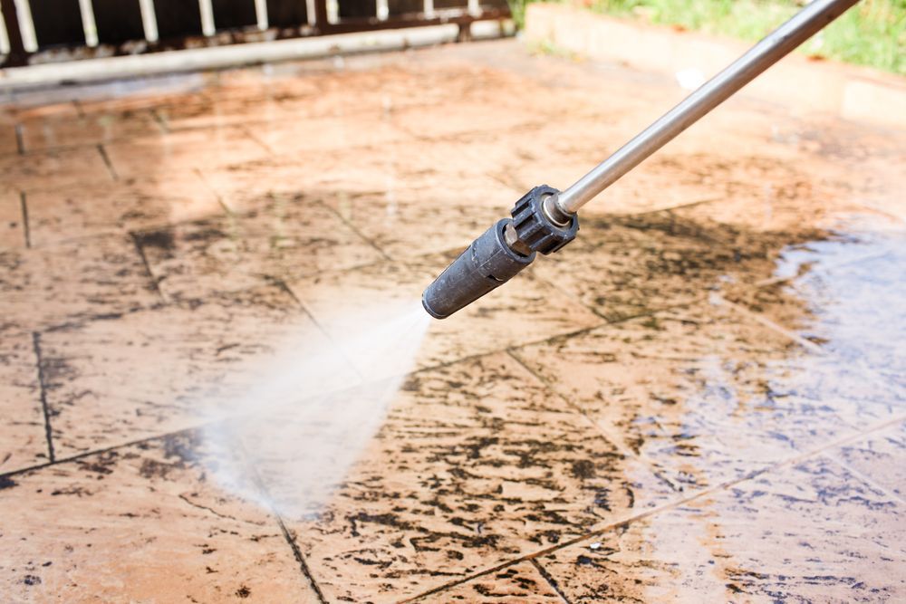 A person is using a high pressure washer to clean a concrete floor.