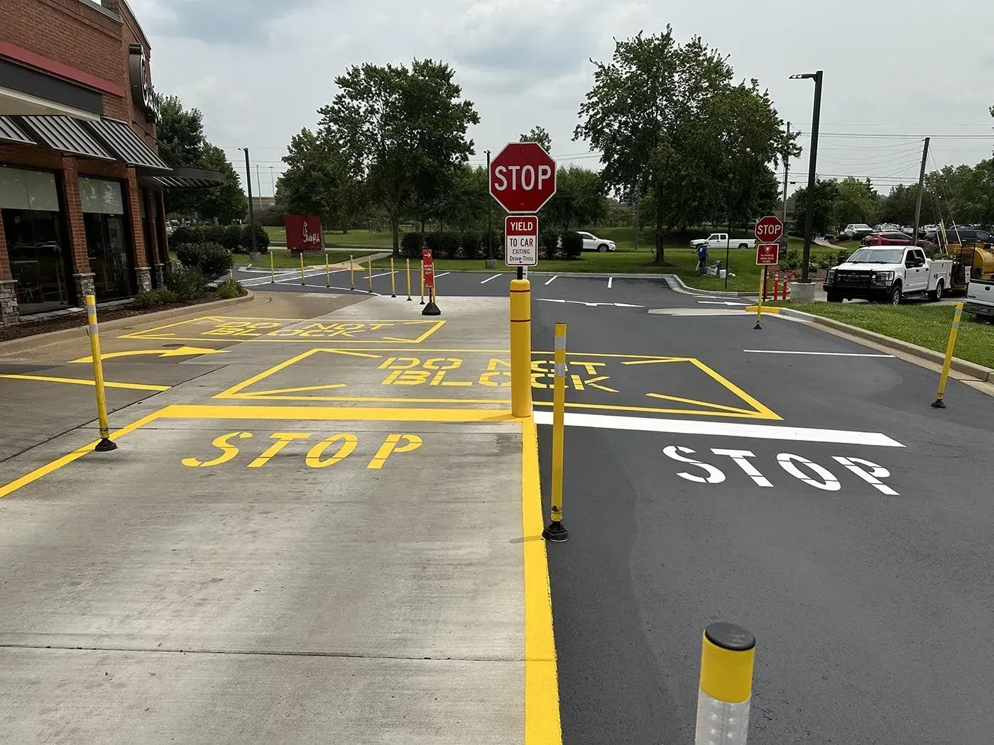 Drive-thru lane with stop signs and yellow painted directions at a fast-food restaurant.