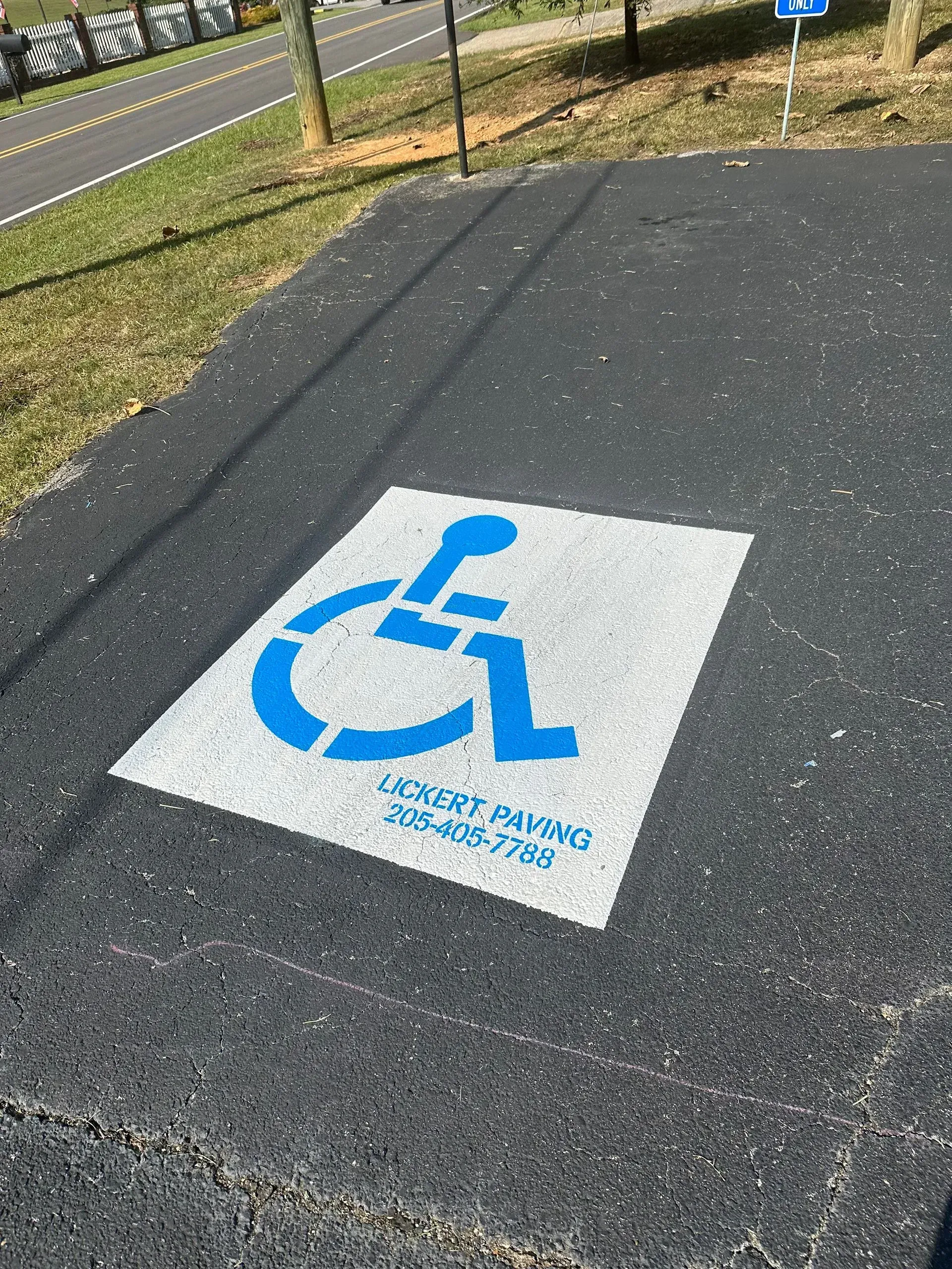 Blue accessible parking symbol painted on a gray concrete surface. 