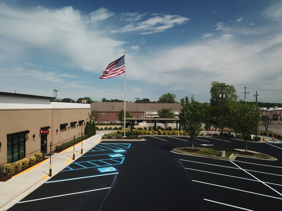 An American flag flies over a commercial building and parking lot with accessible parking spaces marked in blue.