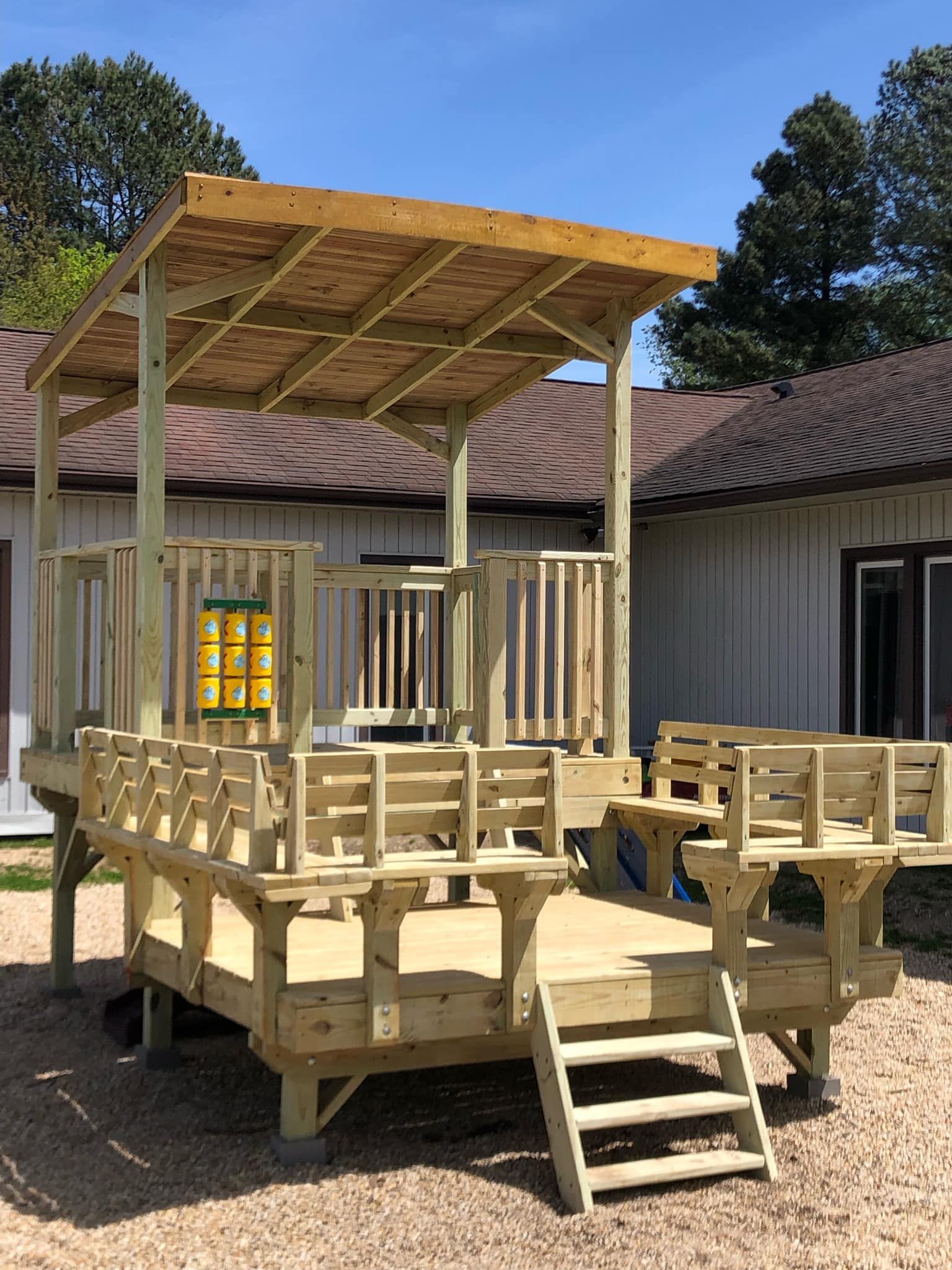 A wooden deck with a canopy and stairs is sitting in front of a house.
