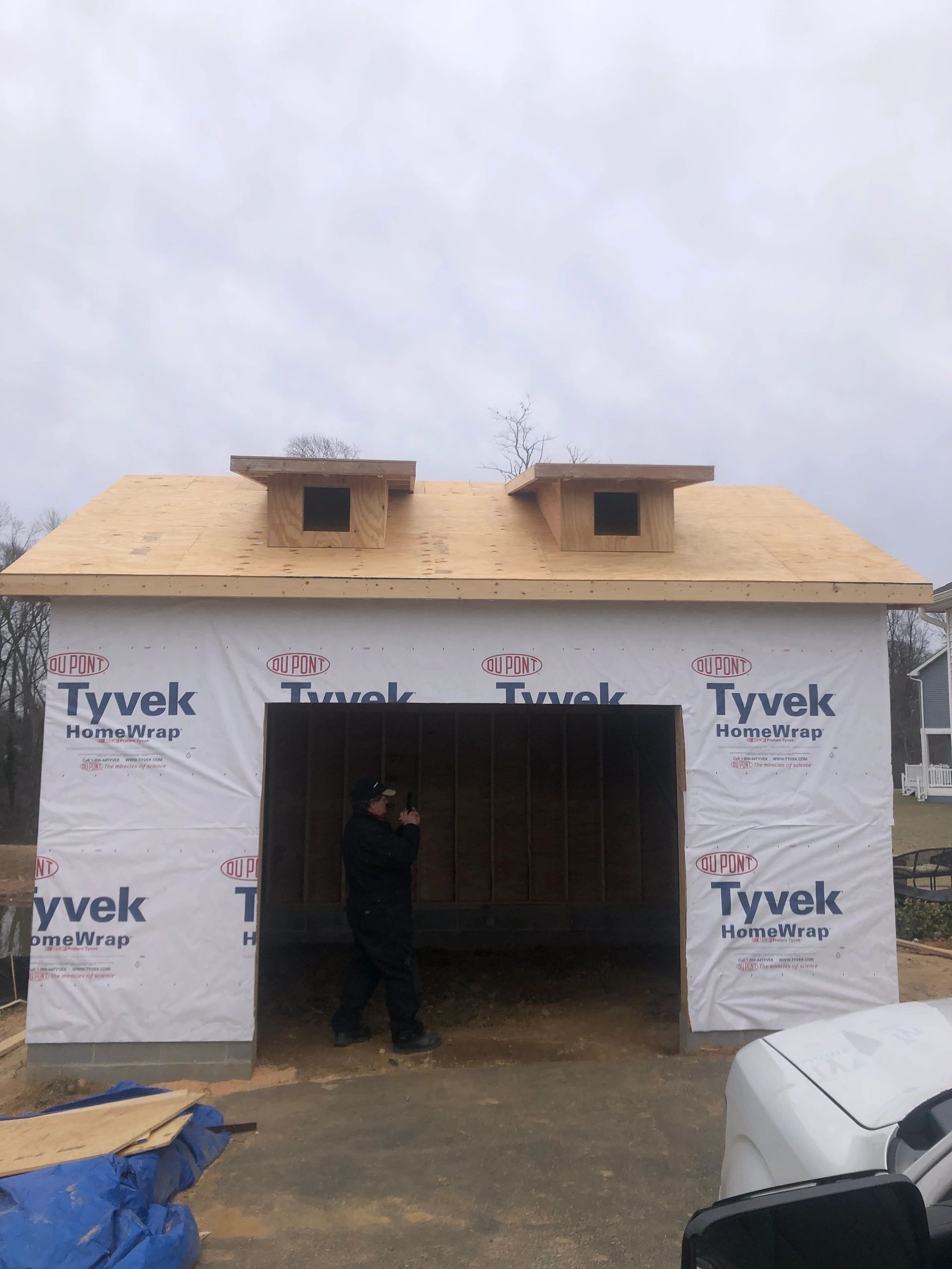 A man is standing in front of a garage under construction.
