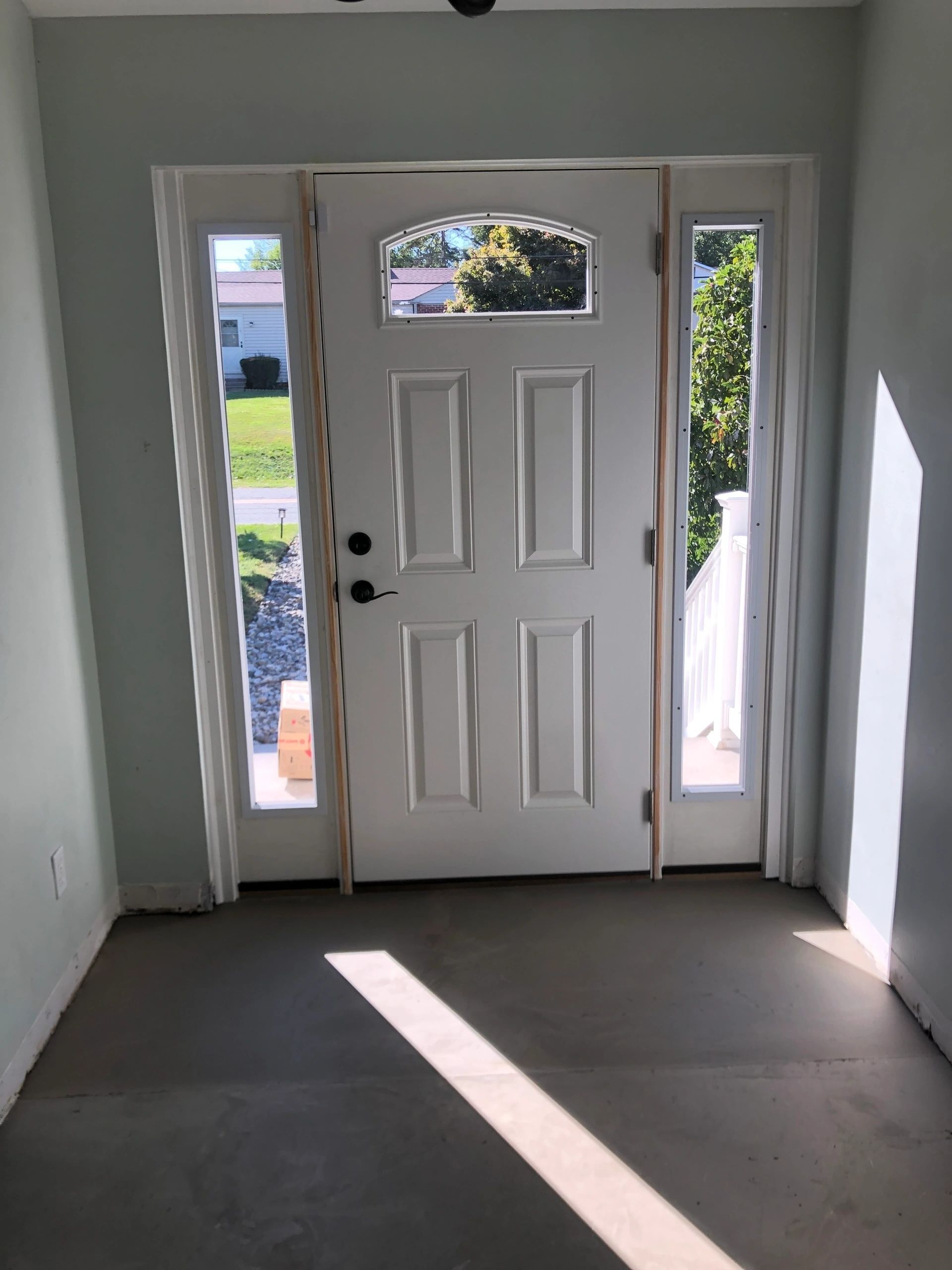 An empty room with a white door and two windows.