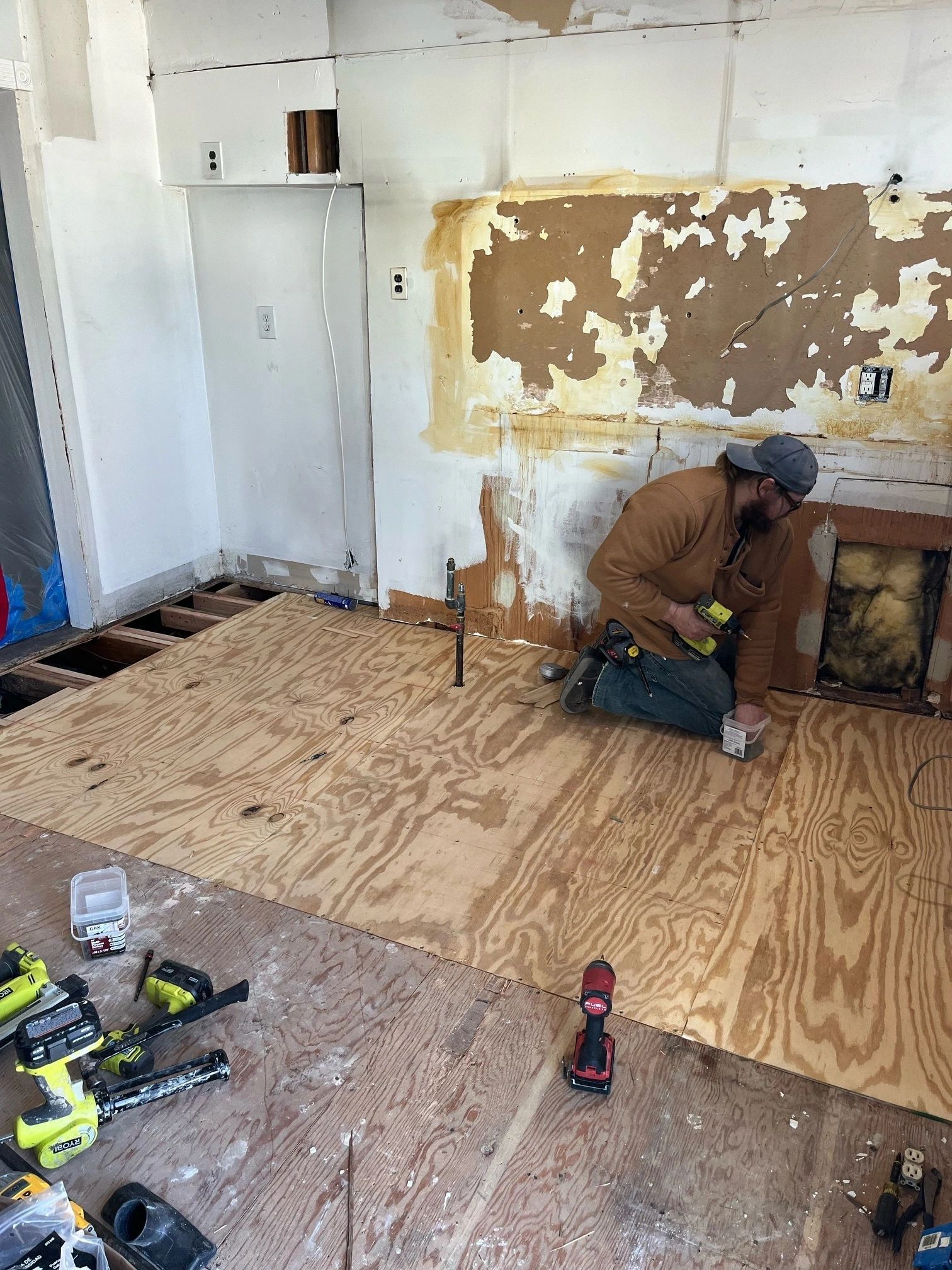 A man is kneeling on a wooden floor in a room.