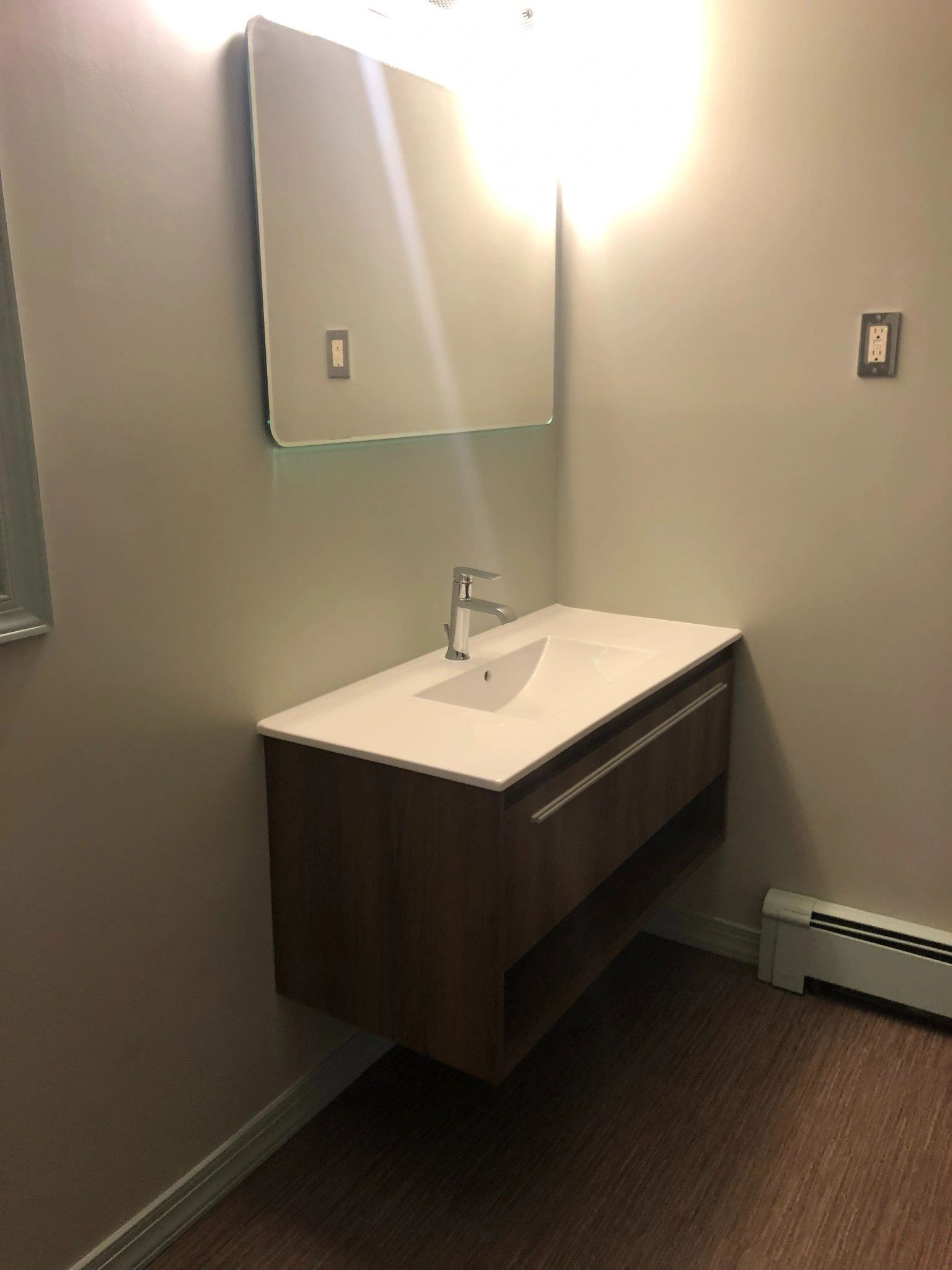 A bathroom with a sink , mirror and heater.