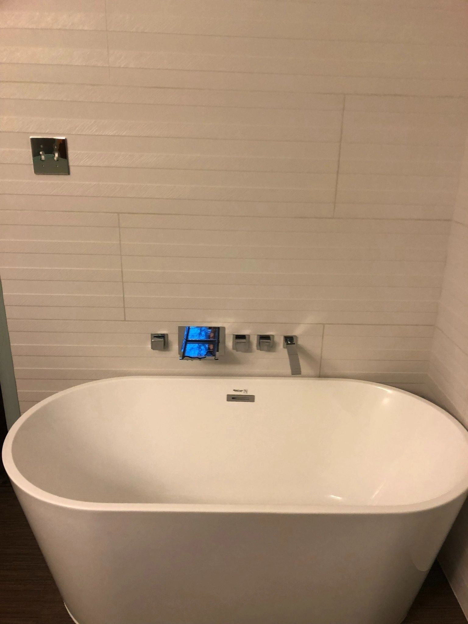 A white bathtub is sitting in a bathroom next to a wall.