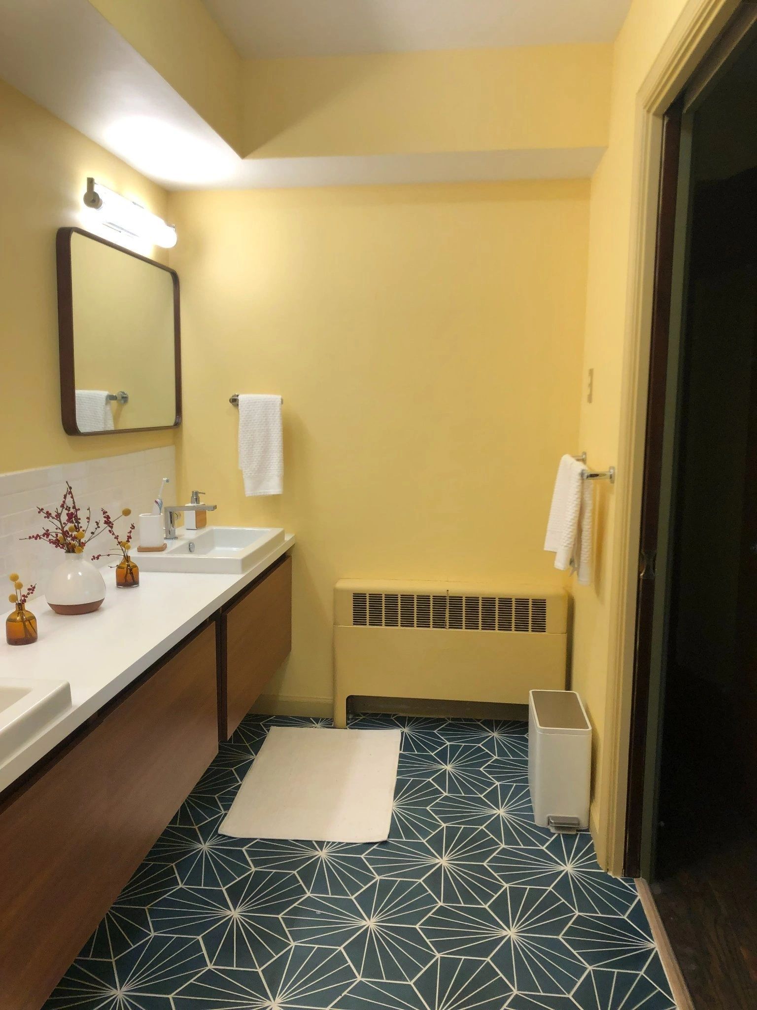 A bathroom with two sinks , a mirror and a radiator.
