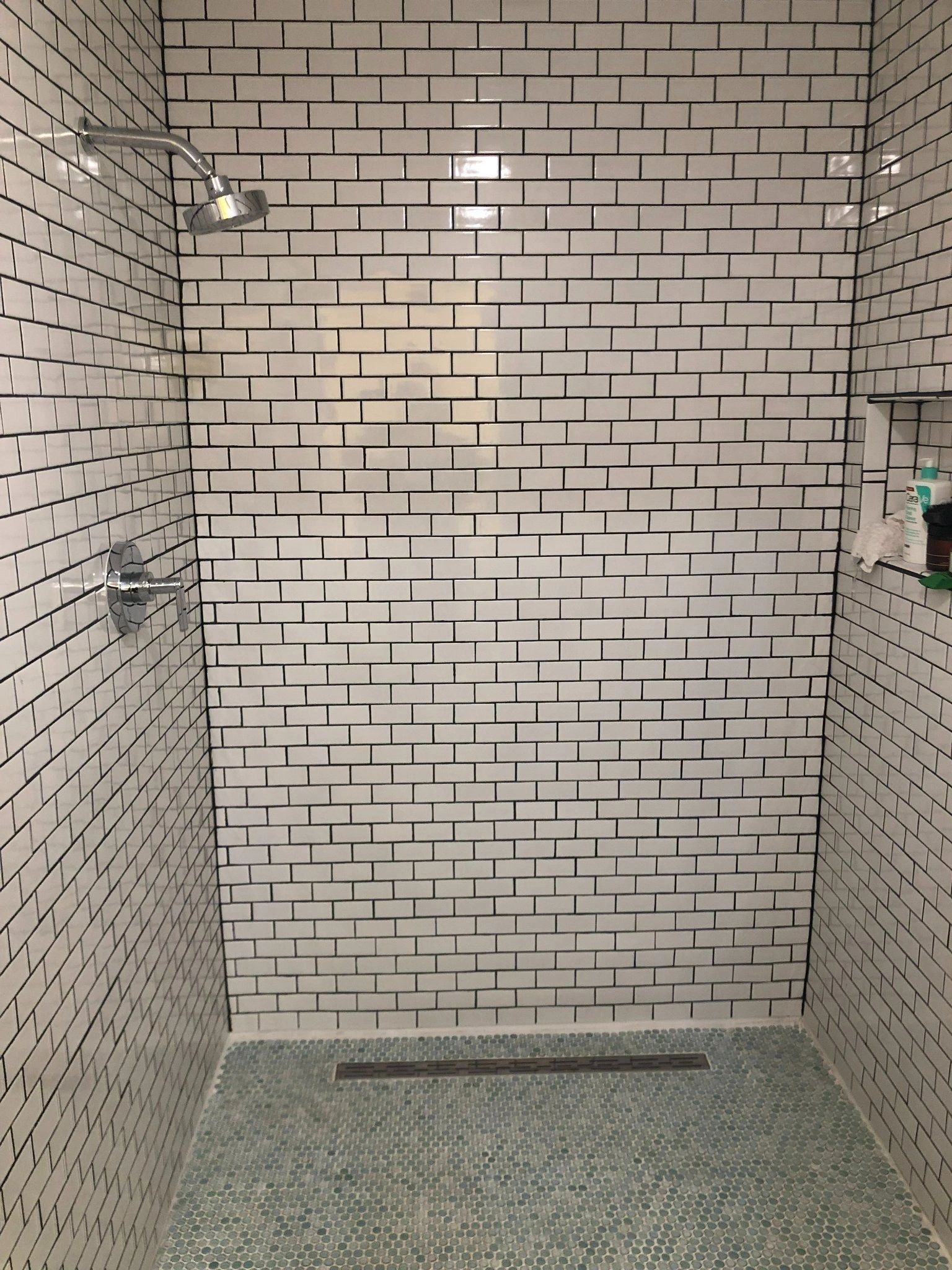 A shower with a black and white brick wall