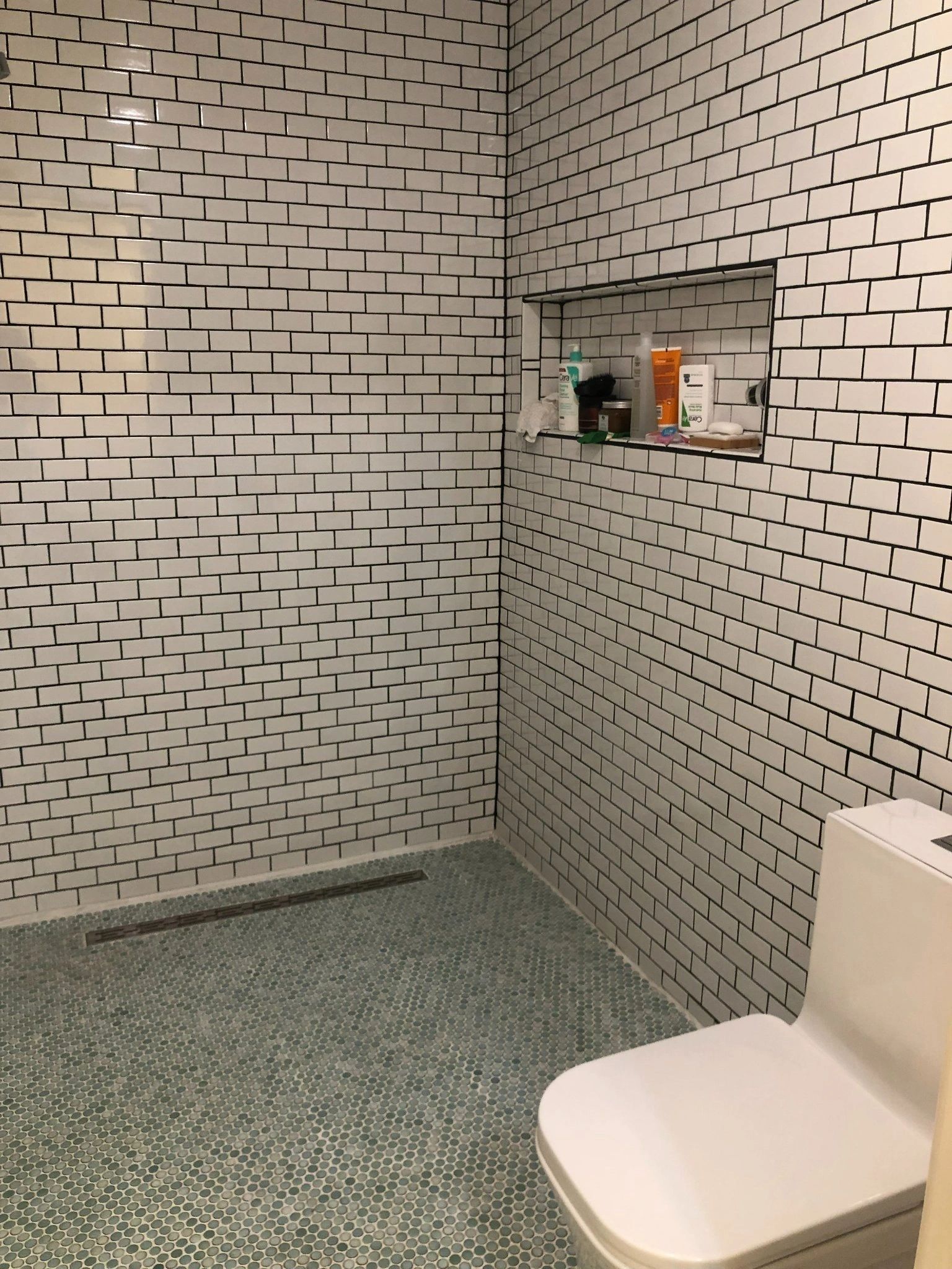 A bathroom with white tiles and a toilet