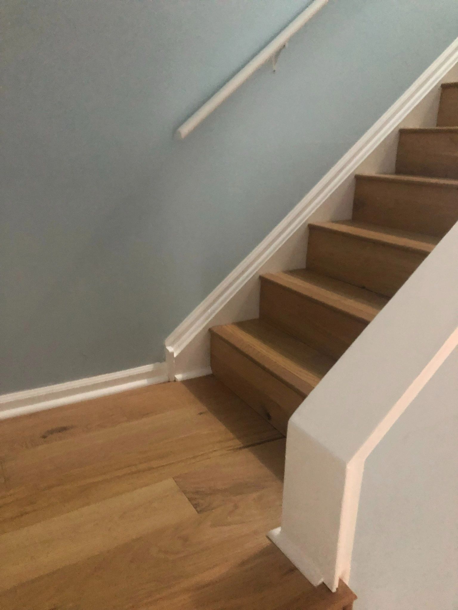 A wooden staircase with a white railing and a blue wall