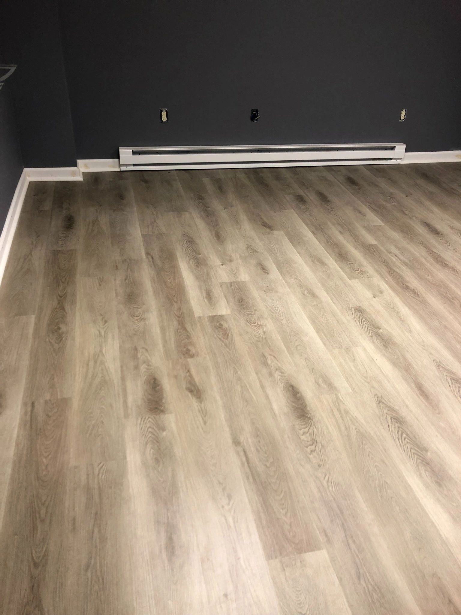 A room with a wooden floor and a gray wall.