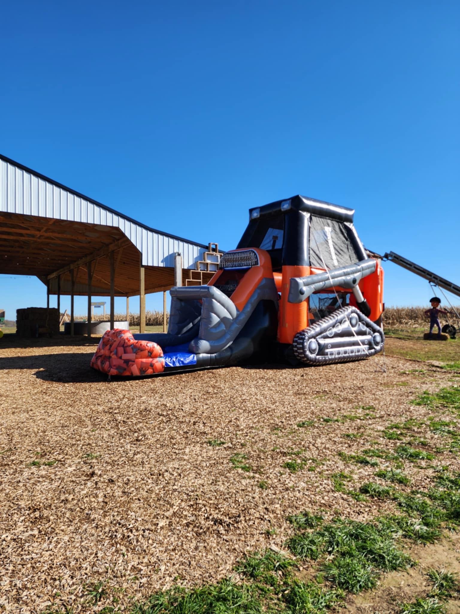 A large inflatable bulldozer is sitting in a dirt field in front of a building.