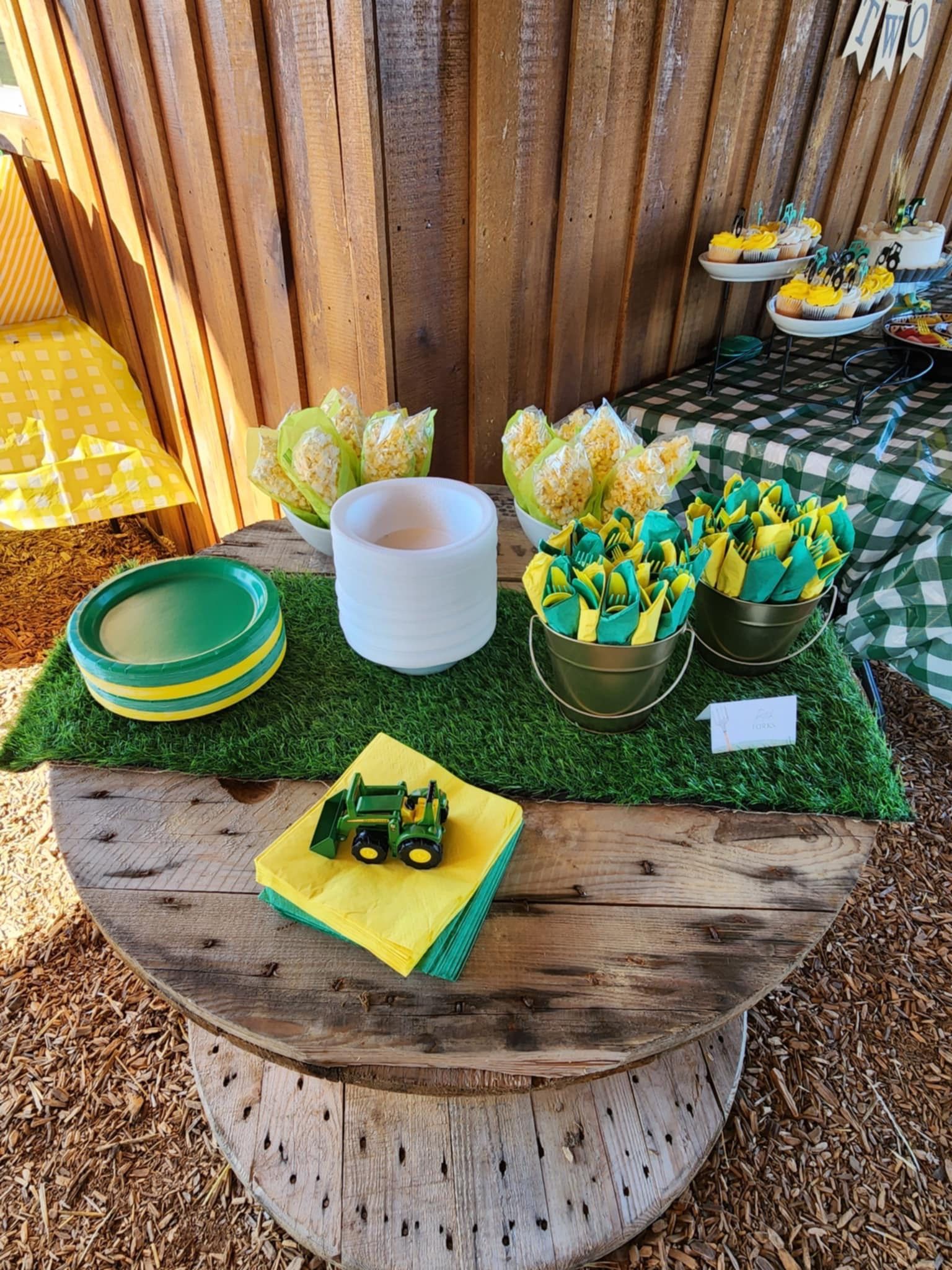 A wooden table with plates , napkins , and a toy tractor on it.
