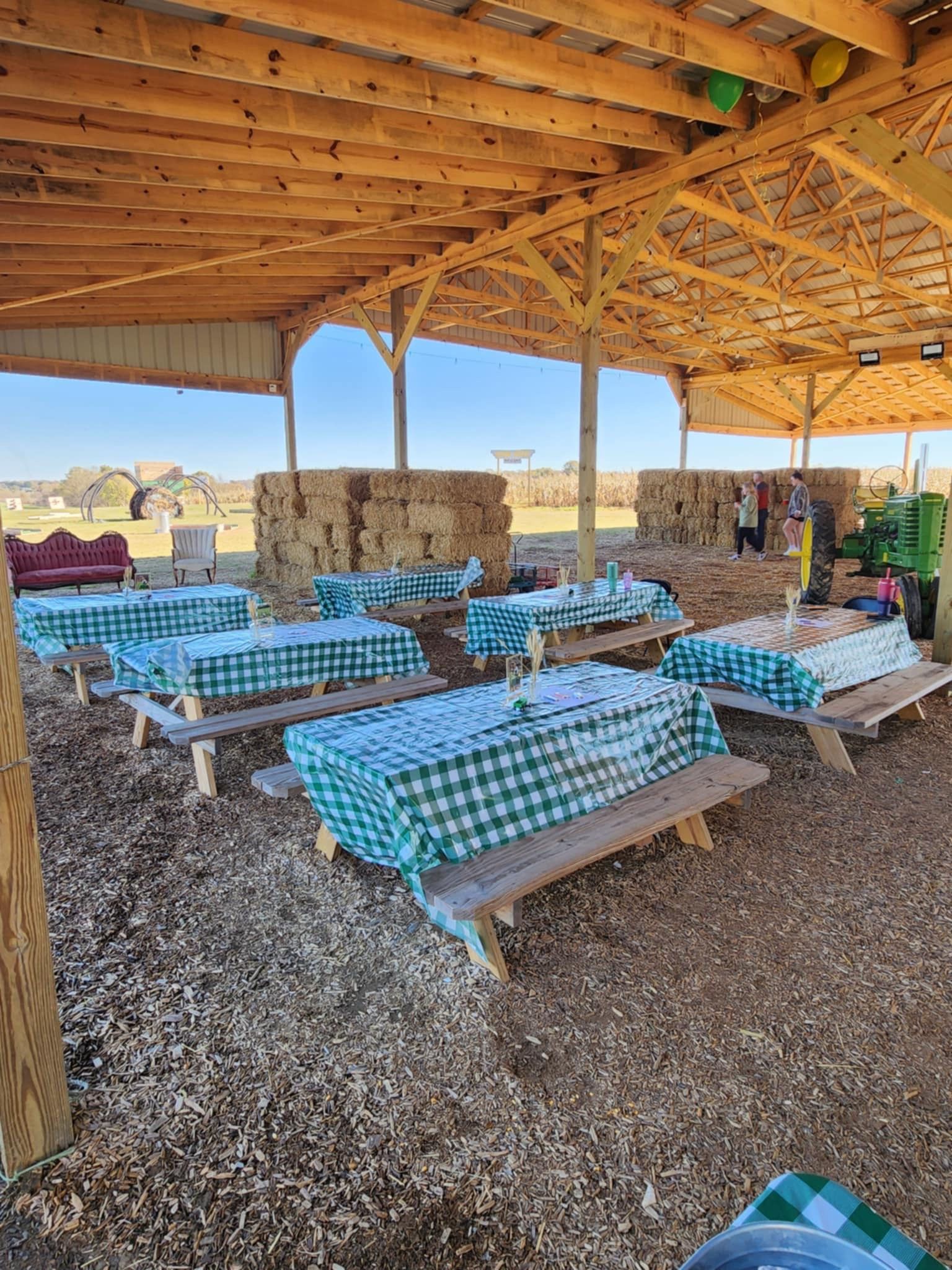 A bunch of tables and benches under a wooden roof.