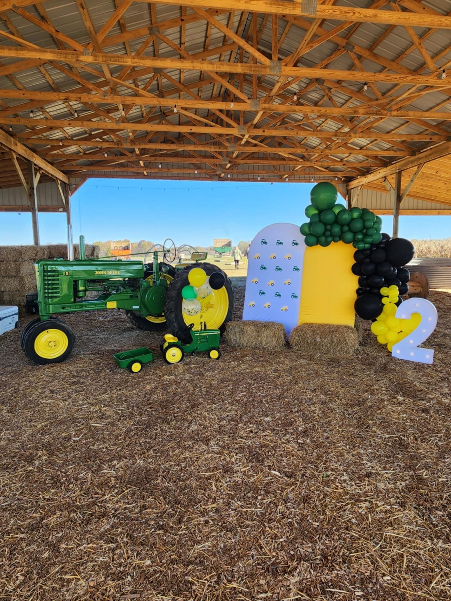 A john deere tractor is sitting in a barn decorated with balloons.