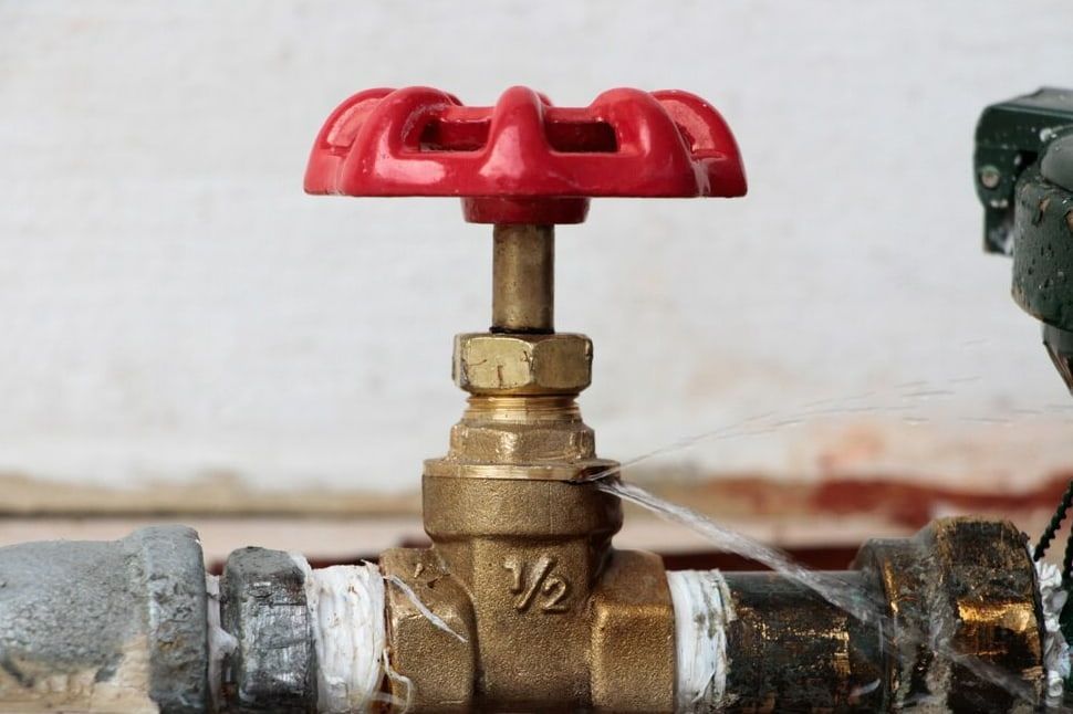 A Close Up Of A Water Valve With A Red Handle On A Pipe — Flavell Plumbing (NT) Pty Ltd In Ciccone, NT