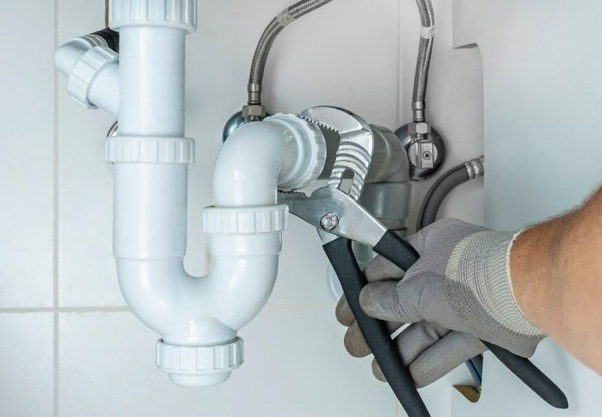A Plumber Is Fixing A Sink Pipe With A Wrench — Flavell Plumbing (NT) Pty Ltd In Ciccone, NT