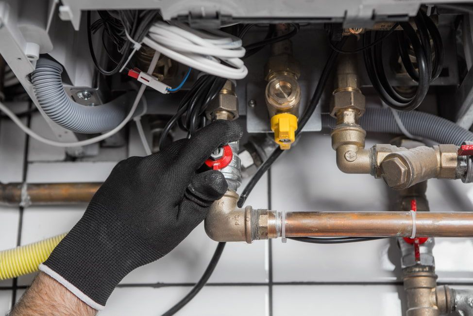 A Person Is Fixing A Boiler With A Wrench — Flavell Plumbing (NT) Pty Ltd In Ciccone, NT