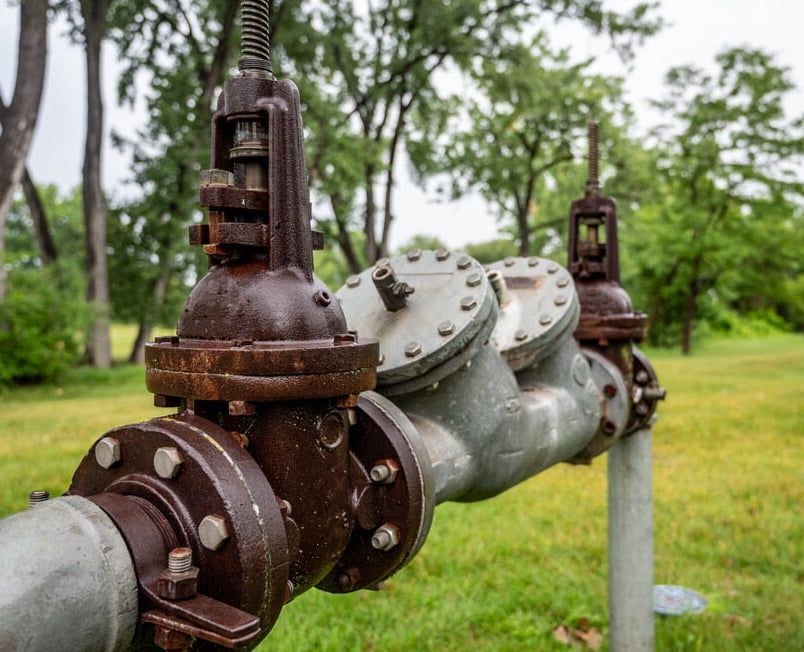 A Close Up Of A Rusty Water Pipe In A Field With Trees In The Background — Flavell Plumbing (NT) Pty Ltd In Ciccone, NT