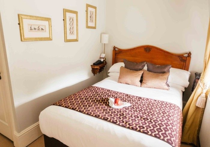 Cozy hotel room with a double bed, framed art, and a small bedside table.