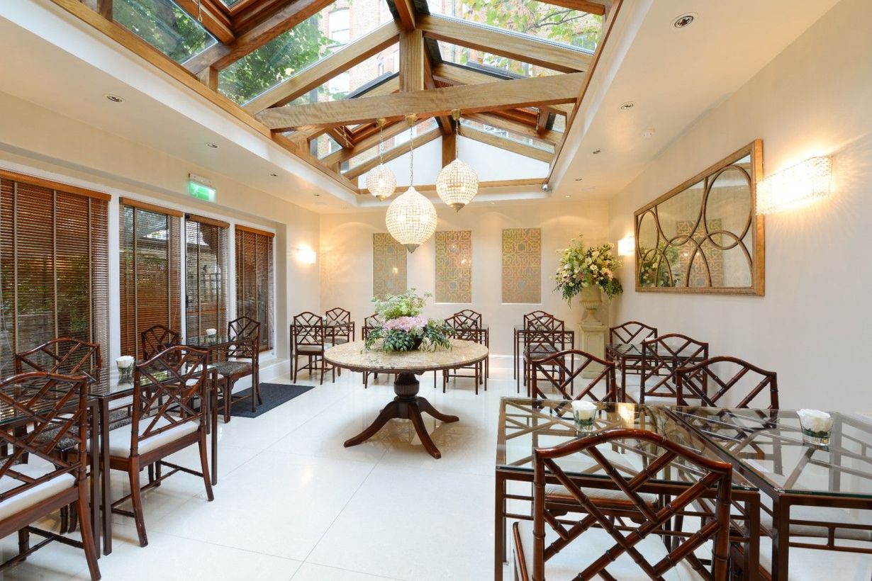 Ceremony room with skylight, wooden beams, round table, chairs, and floral arrangements.