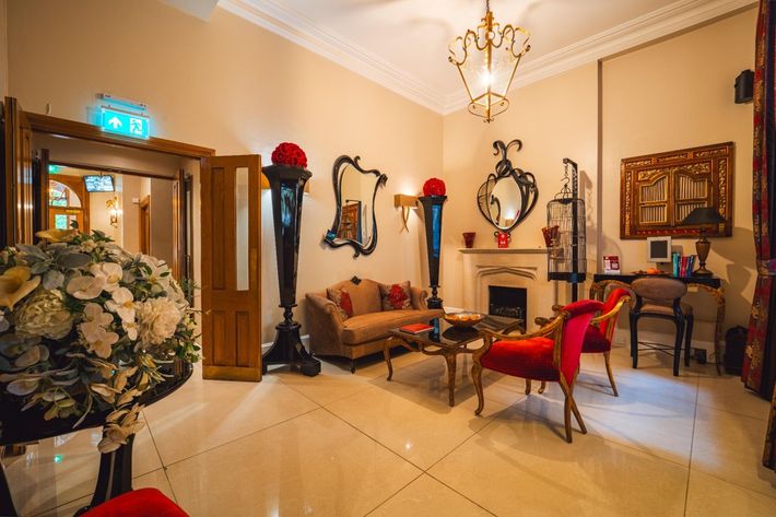 Elegant living room with antique furniture, mirrors, and ornate fireplace.