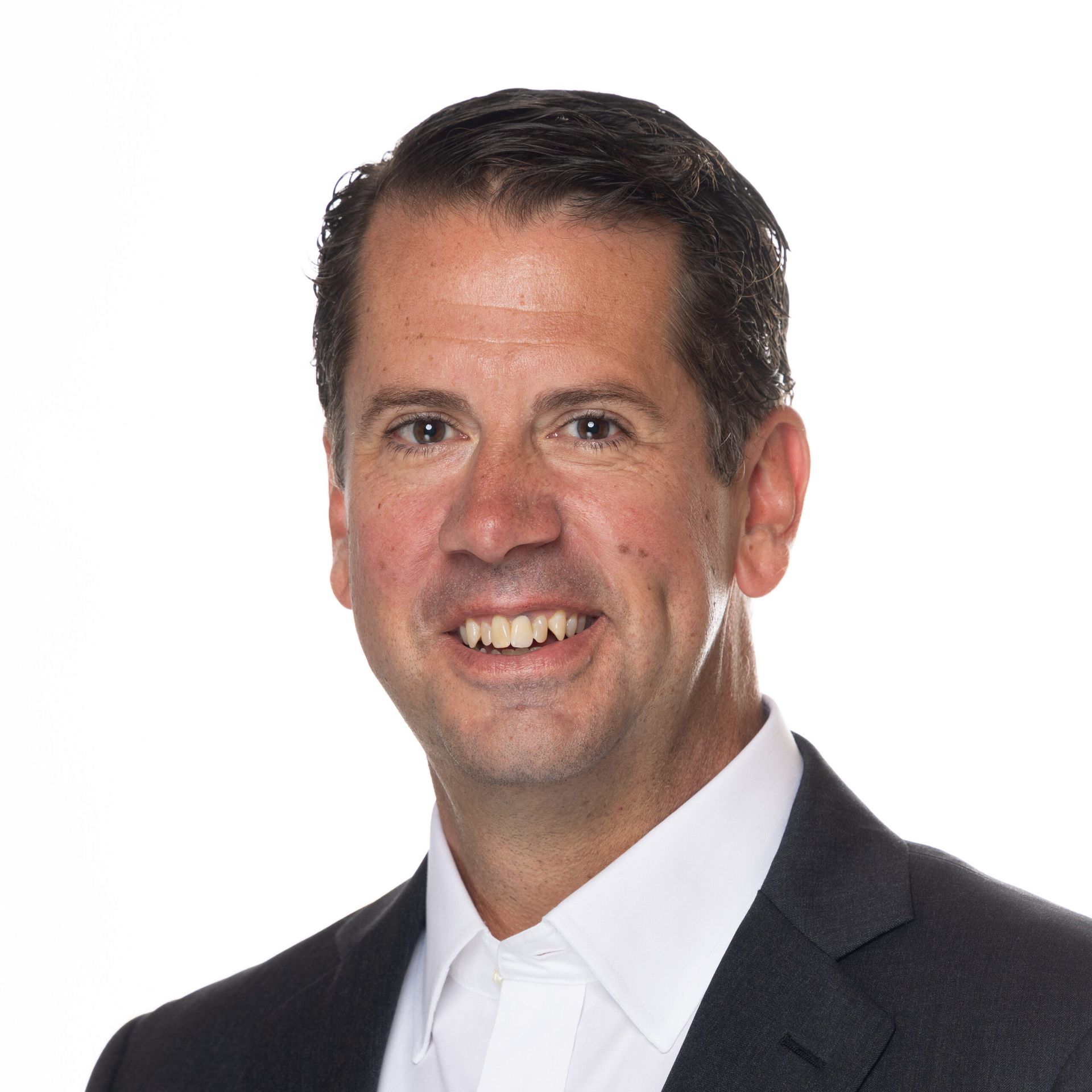 A man in a suit and white shirt is smiling for the camera