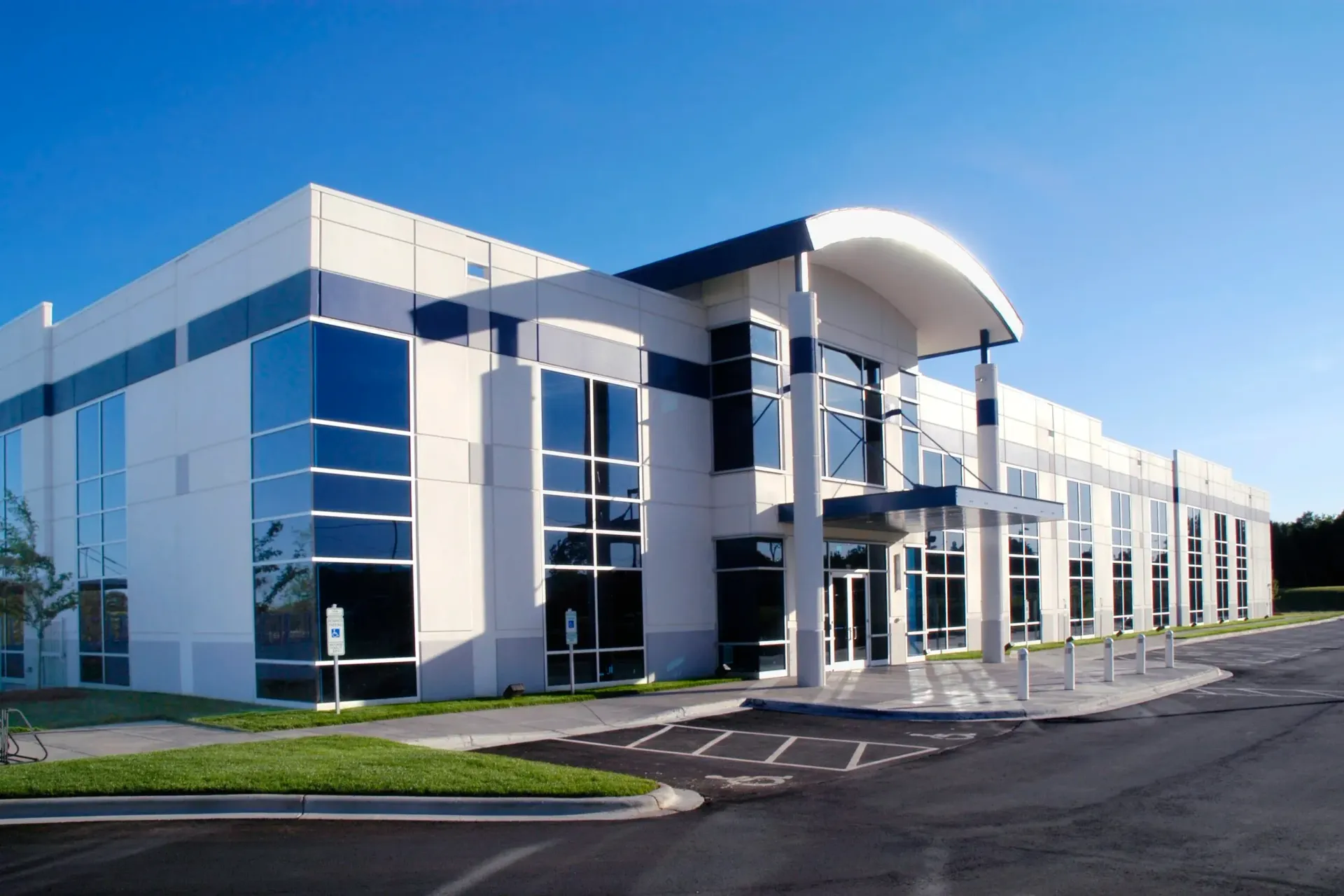 Modern commercial building with glass windows, white and blue facade, sunny day.
