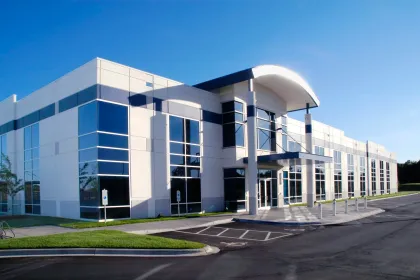 Modern commercial building with glass windows, white and blue facade, sunny day.