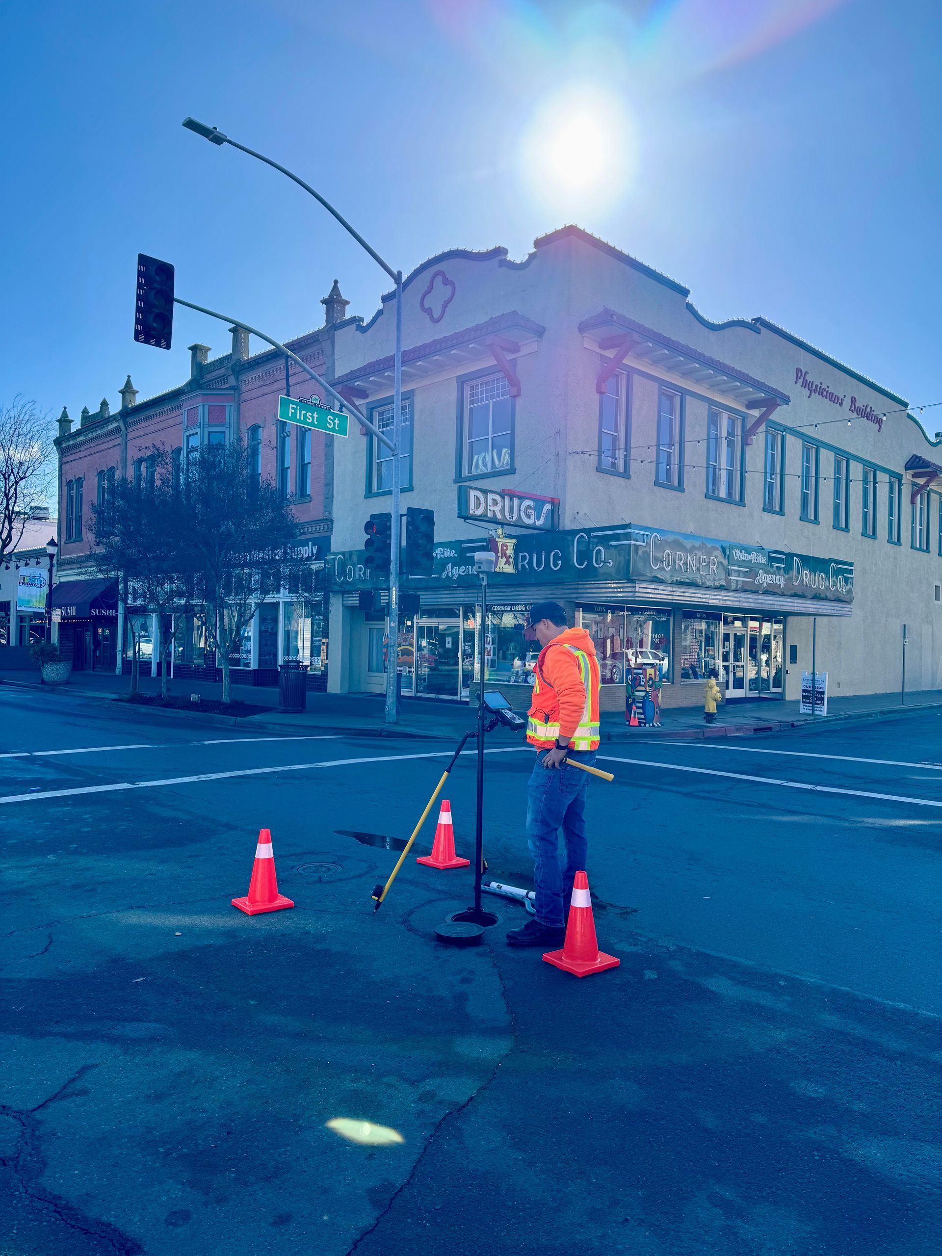 White pickup truck with open tailgate; tripod with equipment next to it, rural setting.