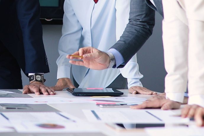 Businesspeople in suits discussing over charts at a conference table