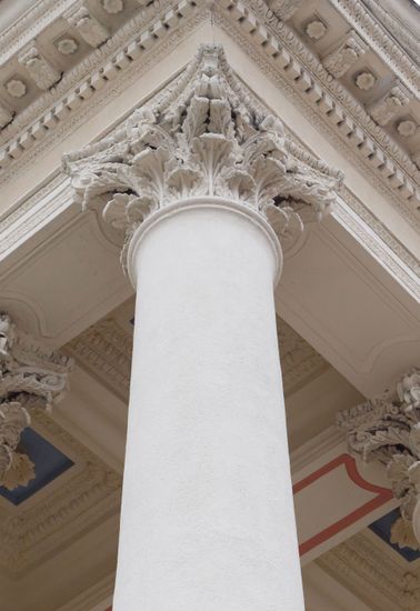 Ornate white column supporting a decorated classical ceiling indoors
