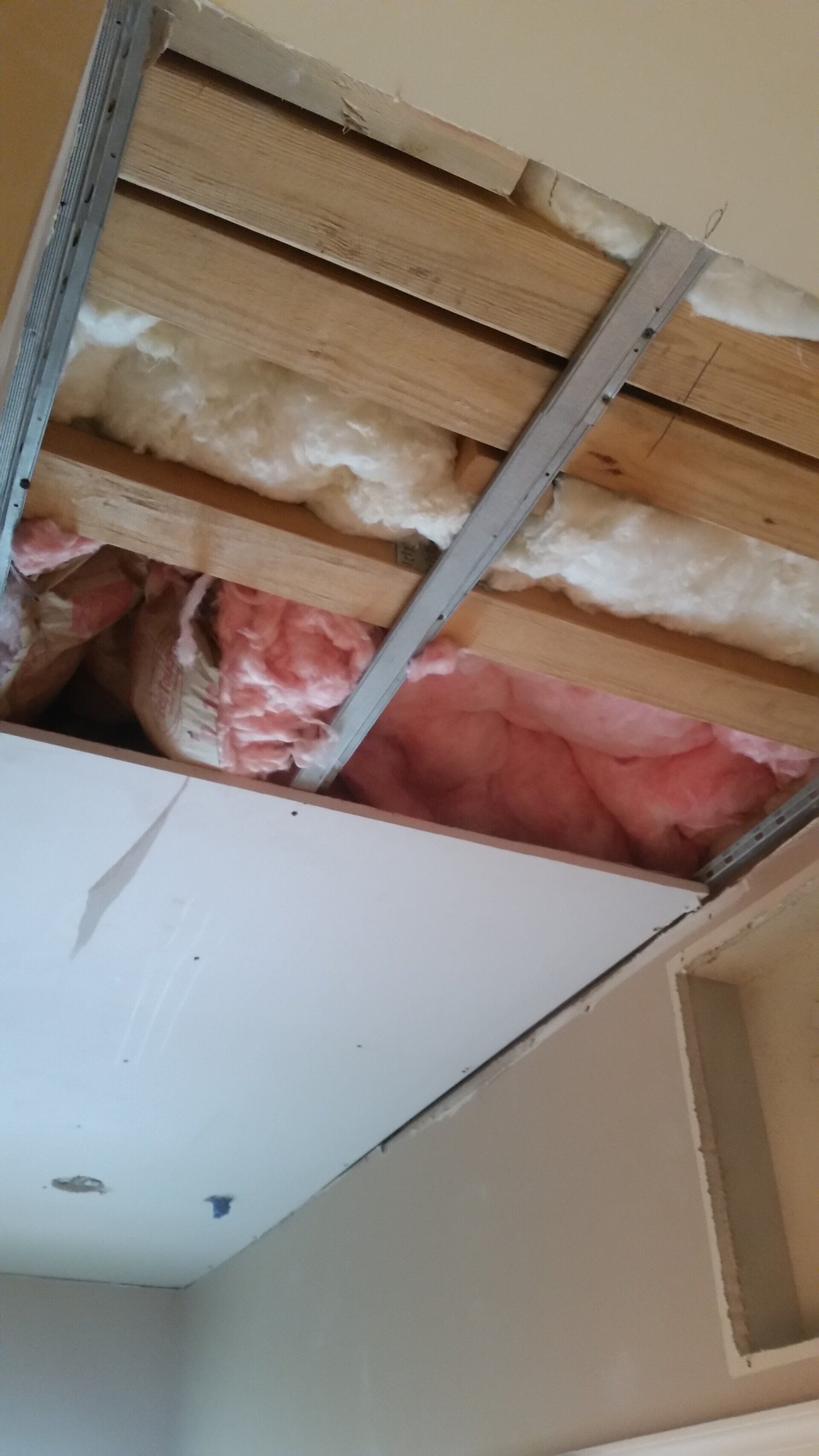 A ceiling with wooden beams and insulation in a room.