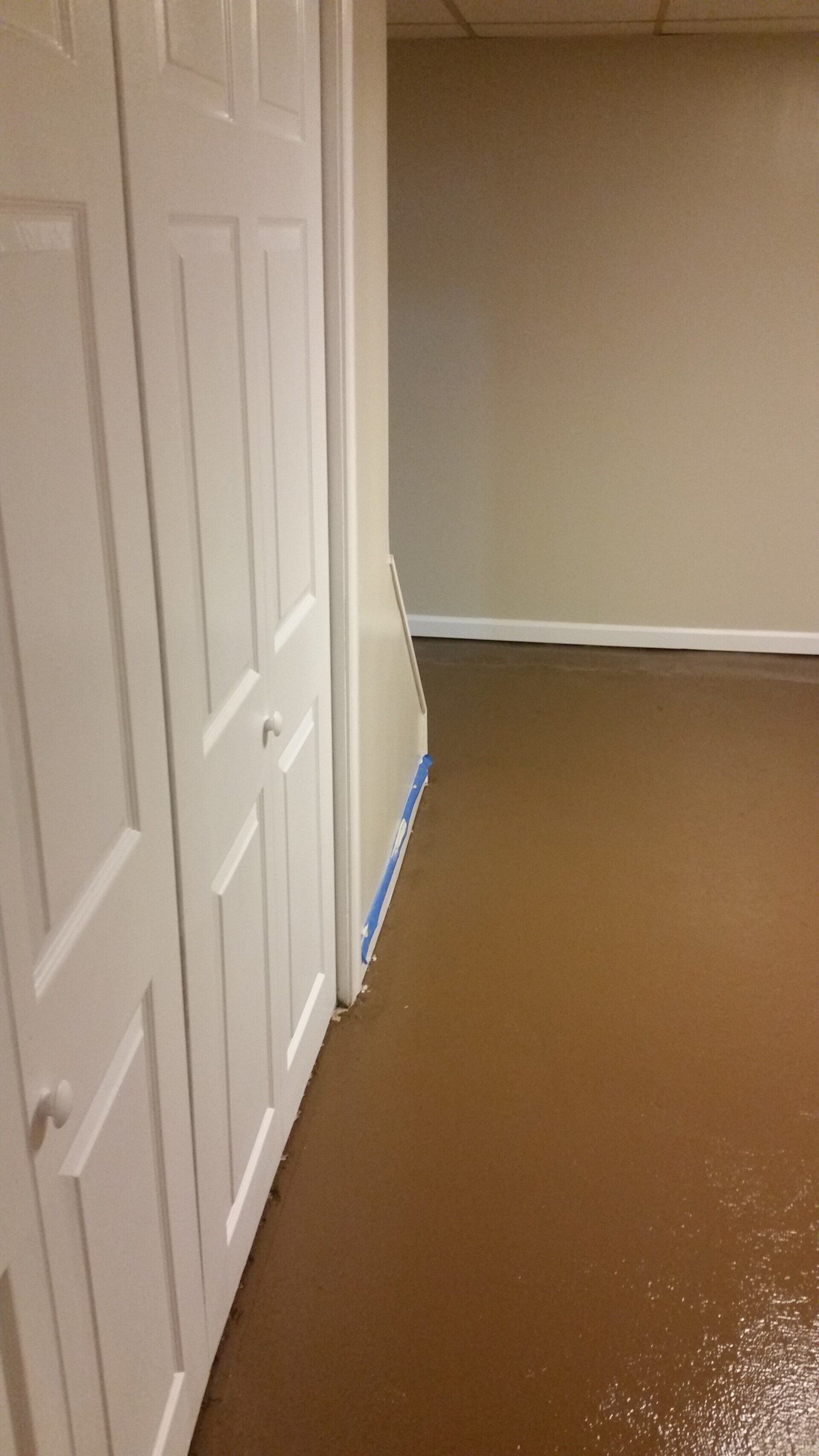 A hallway with a brown floor and white doors in a house.