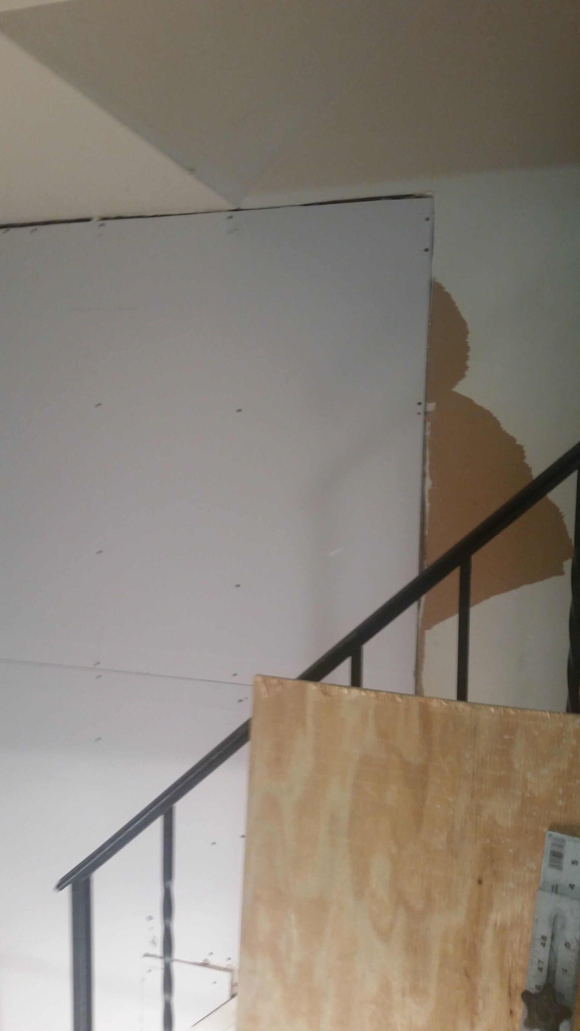 A staircase with a wooden railing and a white wall.